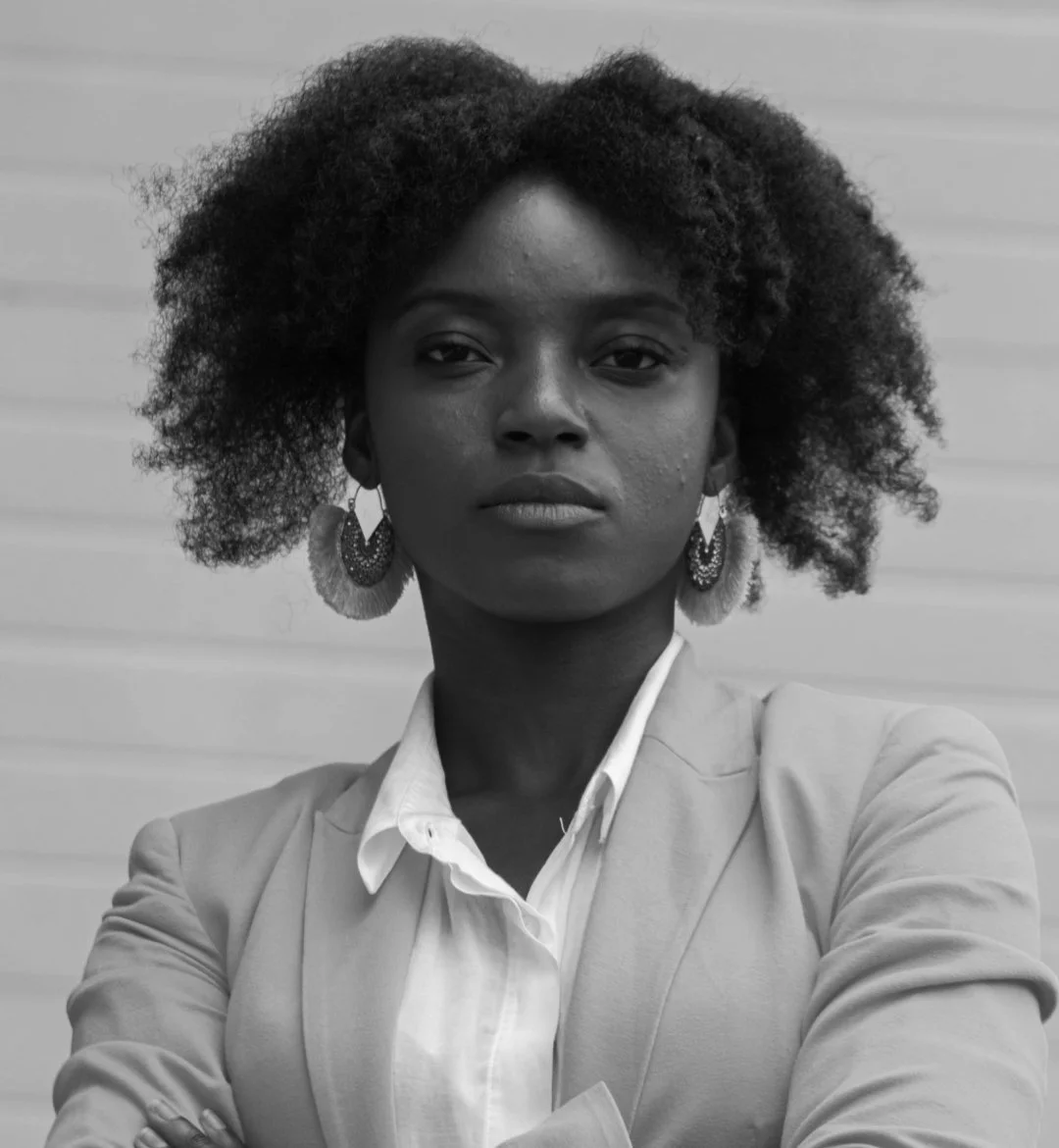 Woman looking directly at the camera with her arms folded across her body, looking self-assured