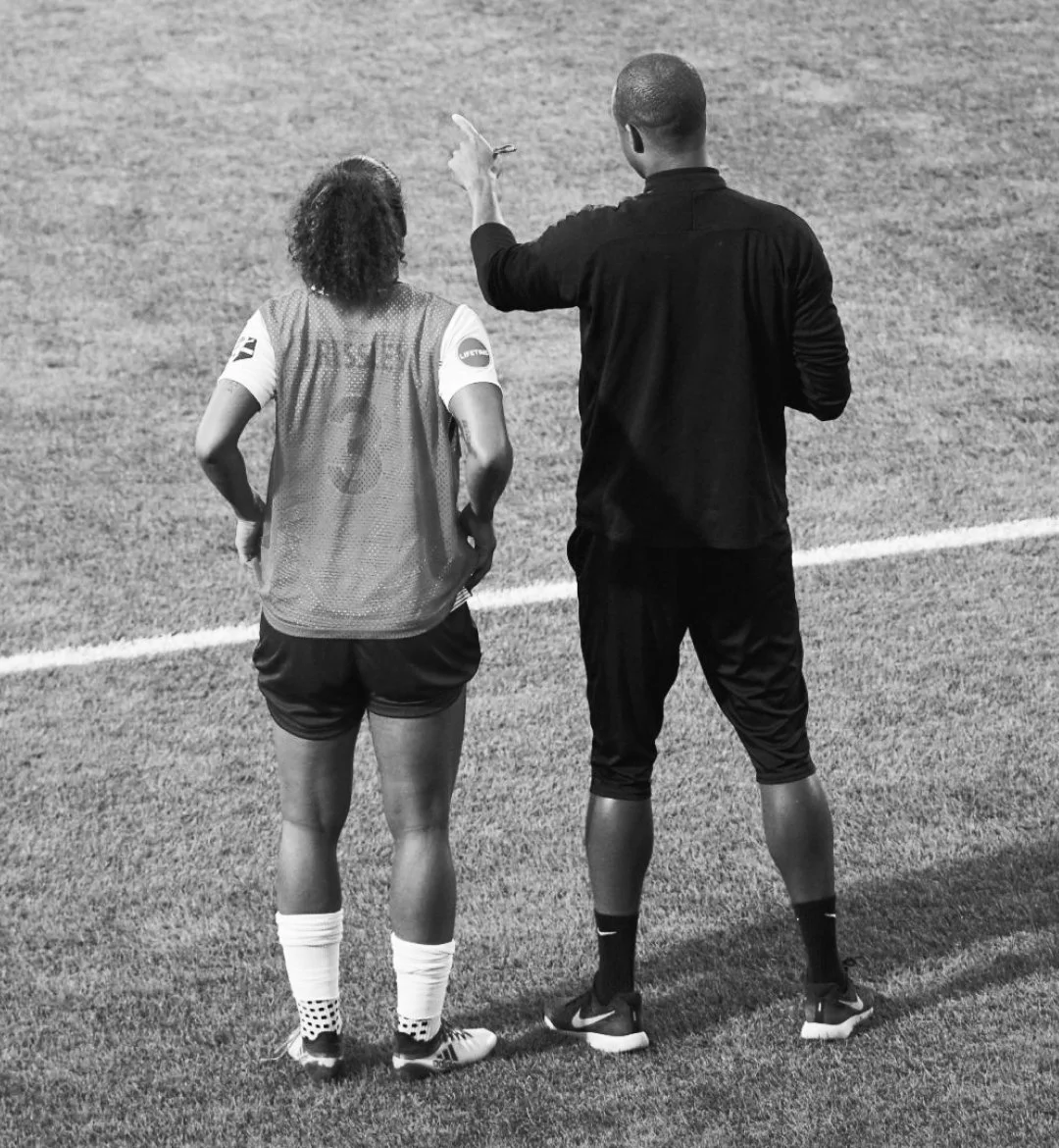 Coach guiding an athlete during training on a sports field