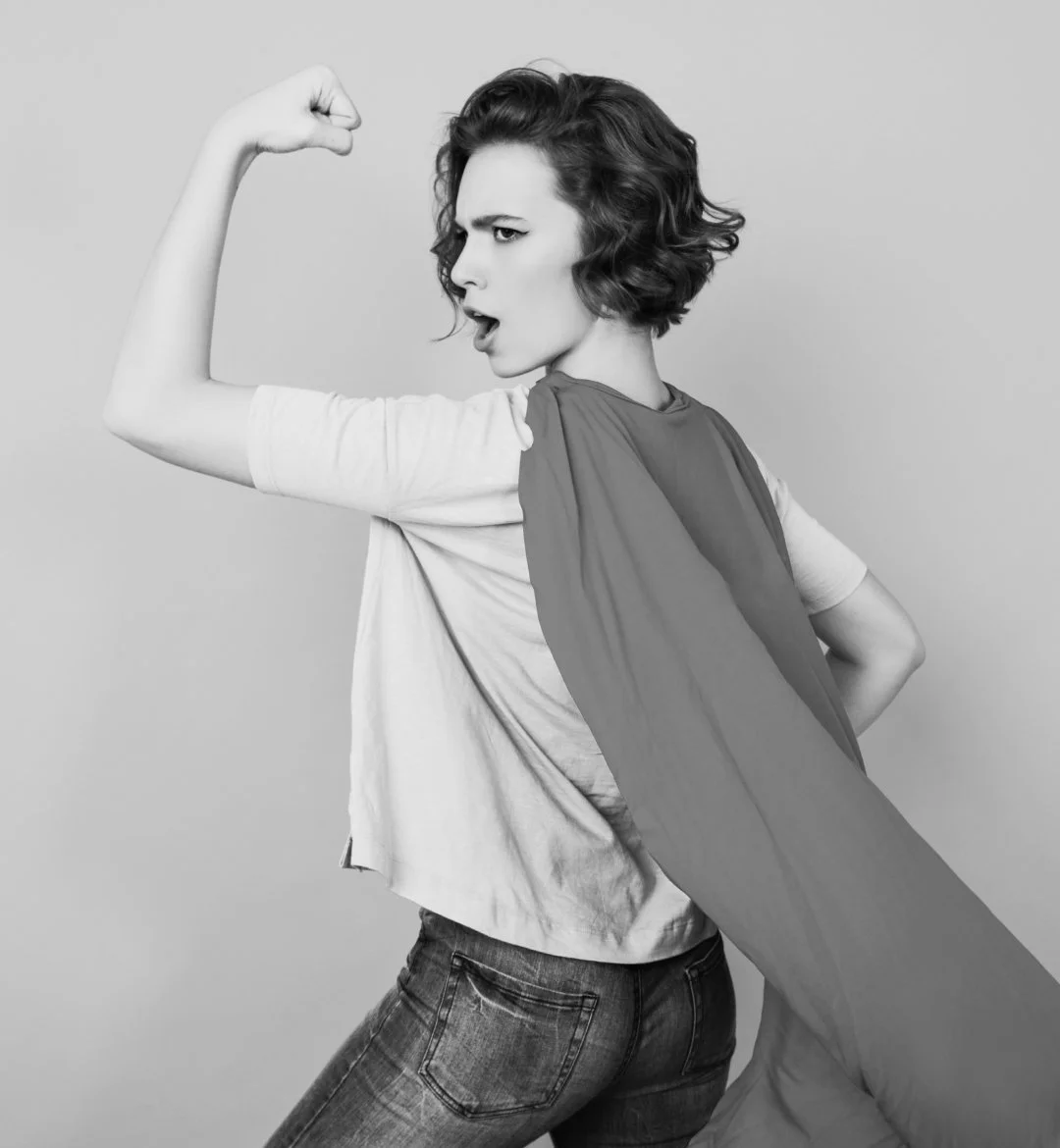 a woman hearing a cape and posting with one arm up like a super hero