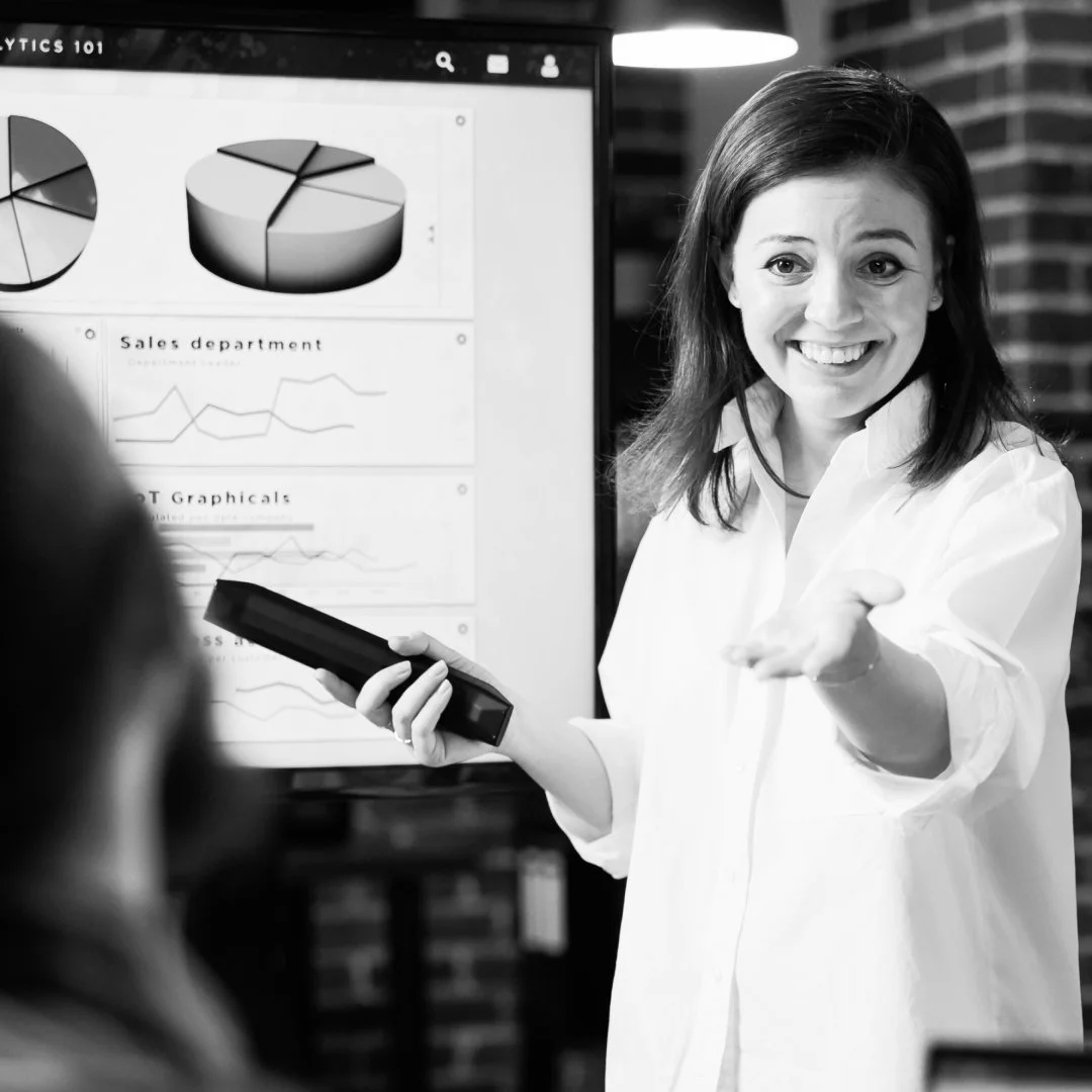 Woman confidently presenting data and engaging with a colleague, representing communication and leadership.