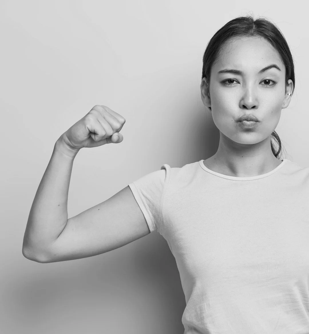 Woman looking at the camera pouting and raising an eyebrow with one arm flexed showing her strength
