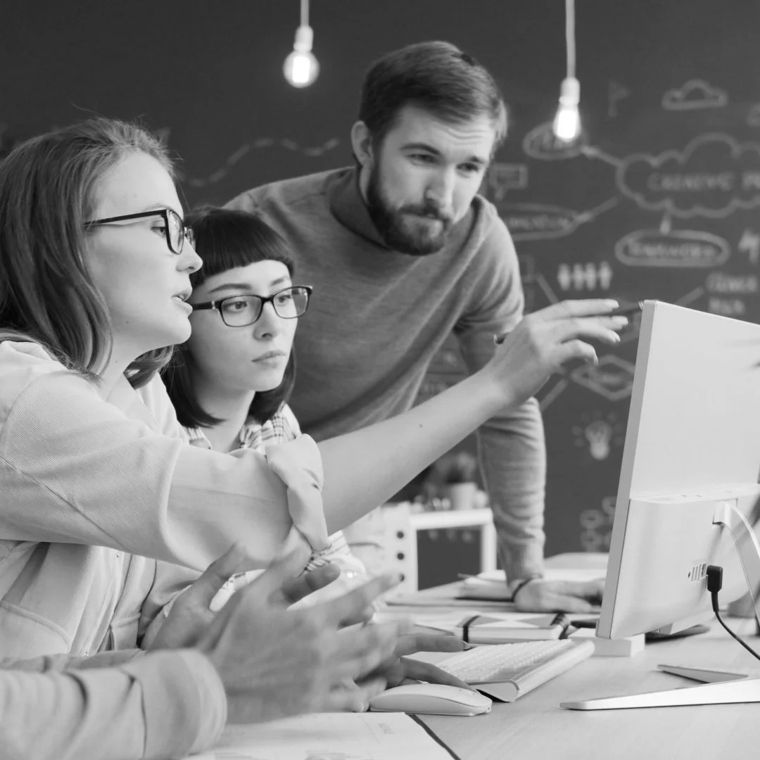 Three people looking at a screen and discussing together