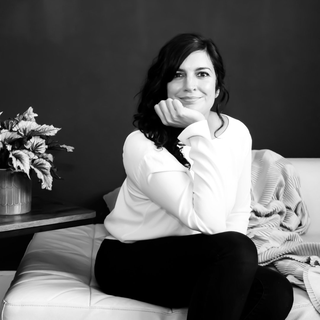 Black and white portrait of Amelia, a coach, sitting comfortably and smiling with a calm, confident expression