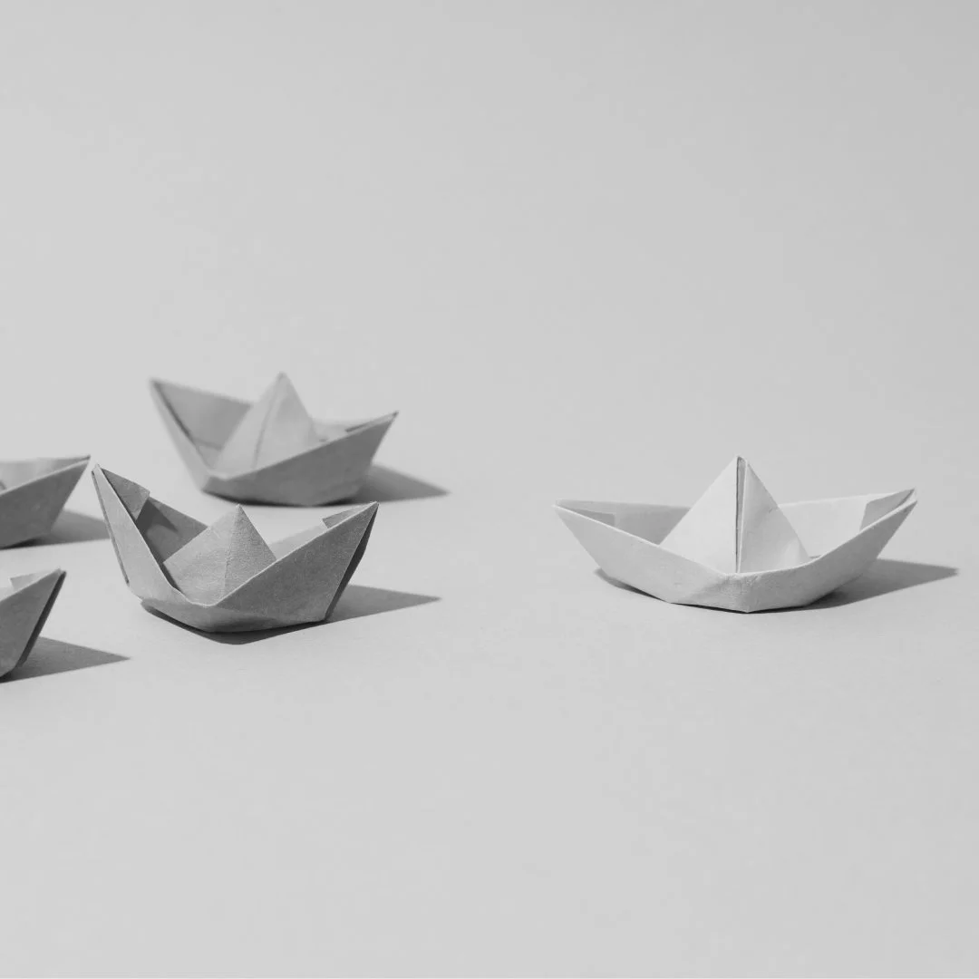 Paper boats with one set apart from the group, representing leadership and individuality.