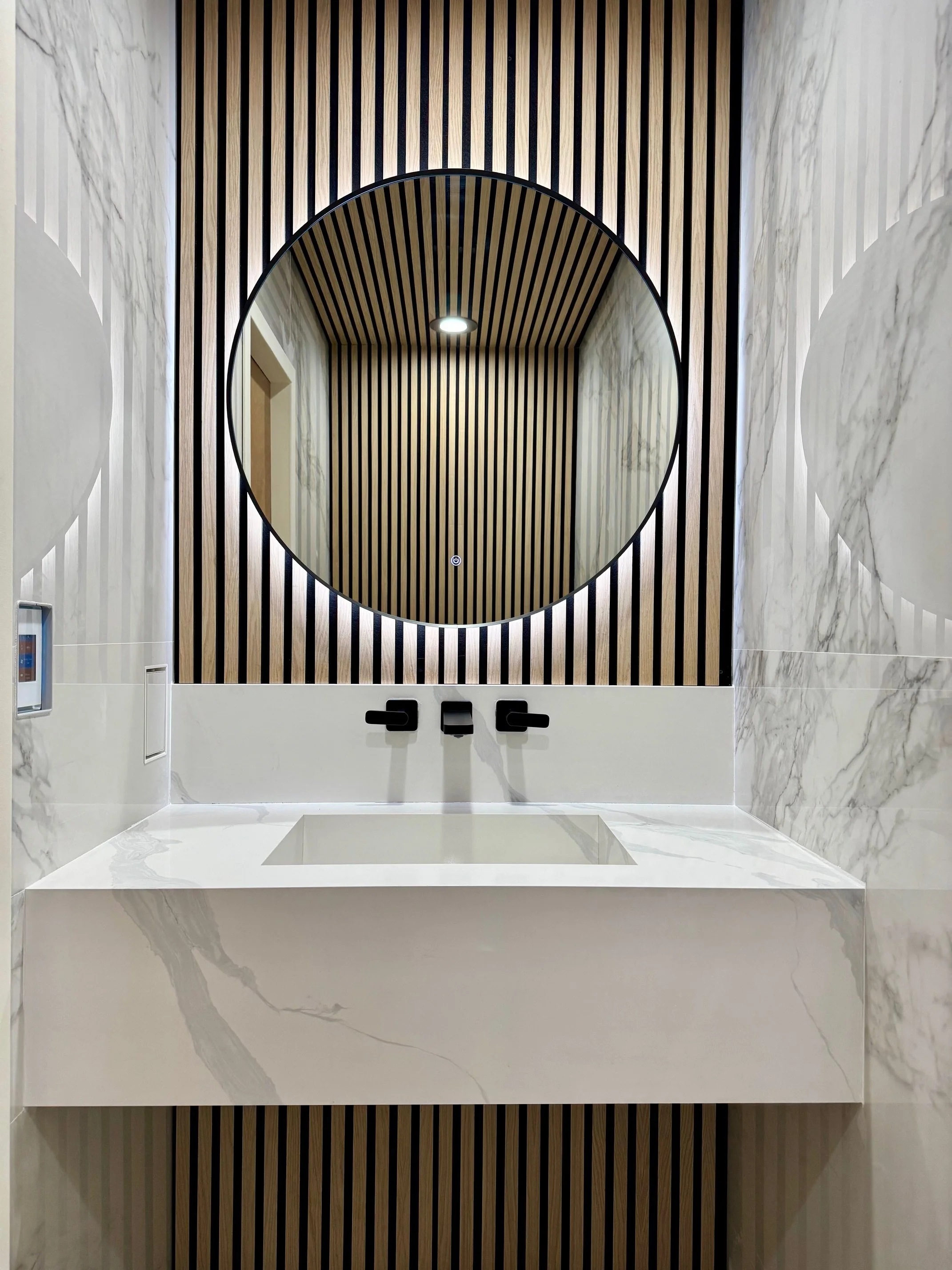 Finished powder room with walnut slat walls, marble, and custom stone vessel sink