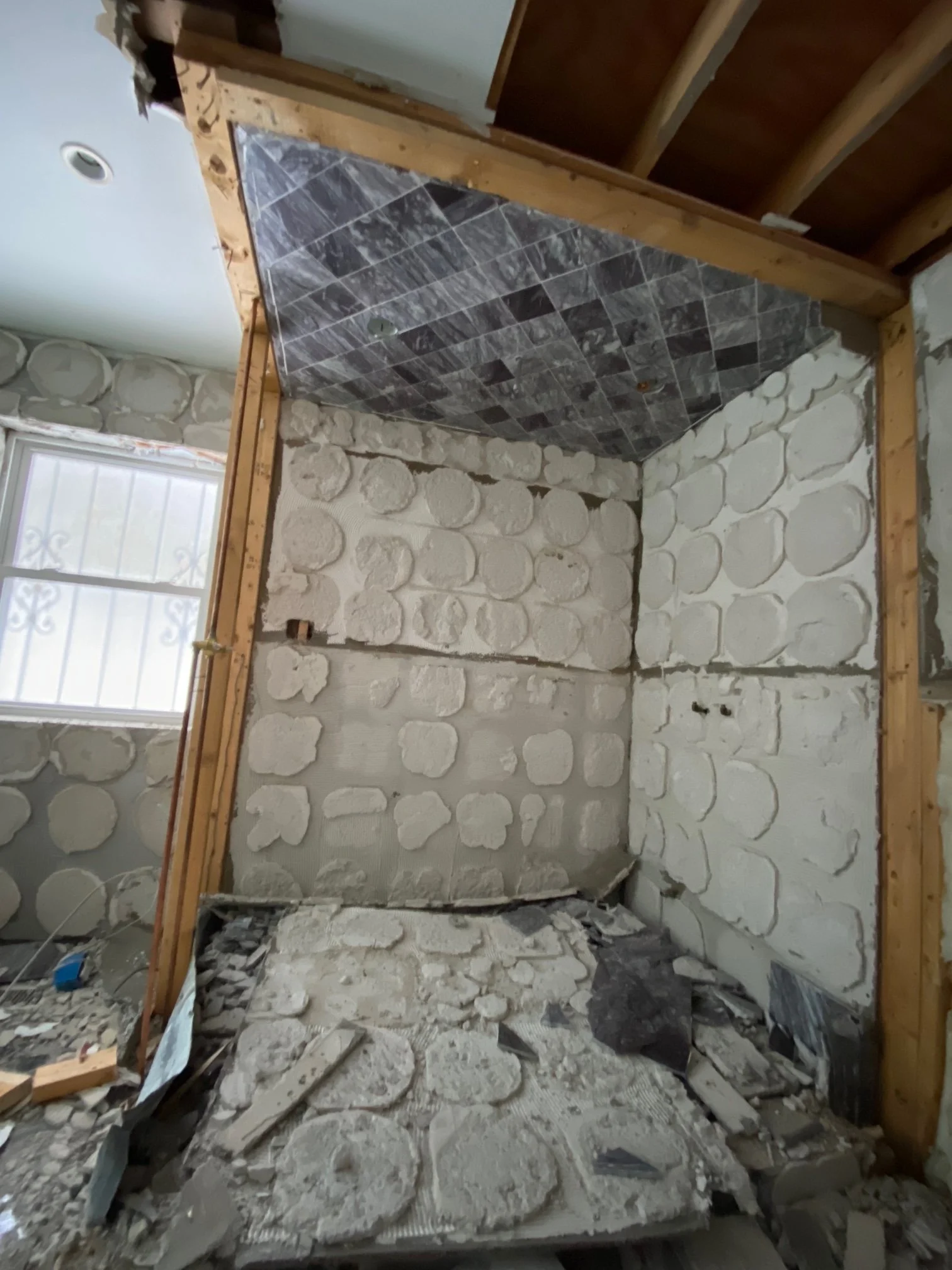 Construction site inside a building with partially finished walls and flooring, debris on the floor, and exposed wooden framing.