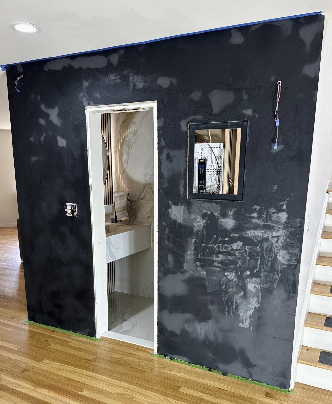 Applying microcement to the door, with concealed electrical panel visible