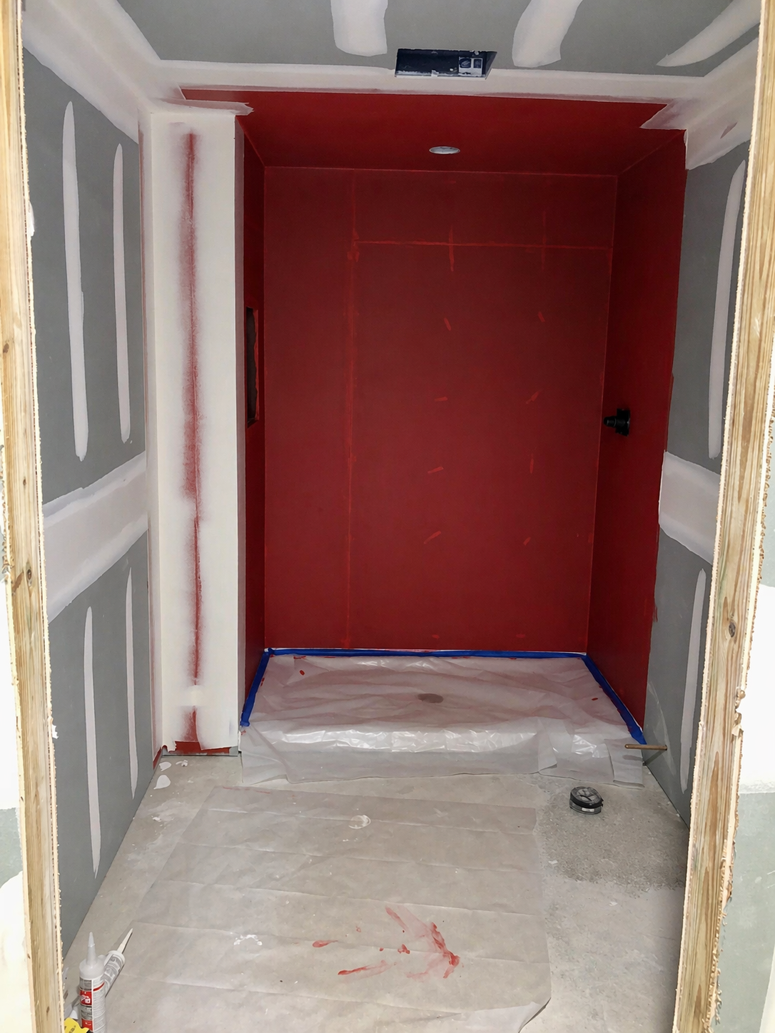 Shower enclosure with red waterproofing membrane applied to walls