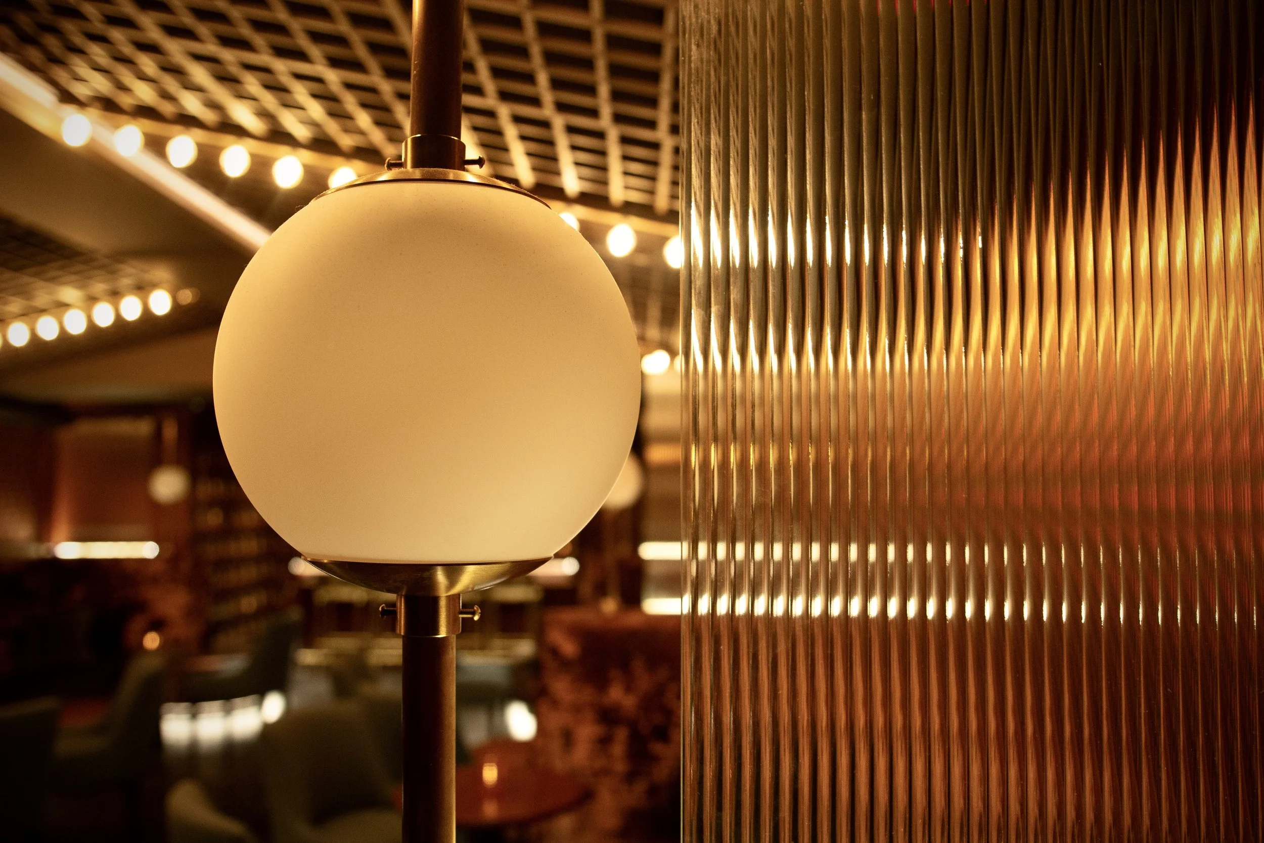 Alexander Mann hospitality interior design, Torches lounge New York, custom globe pendant lamp, fluted glass panel