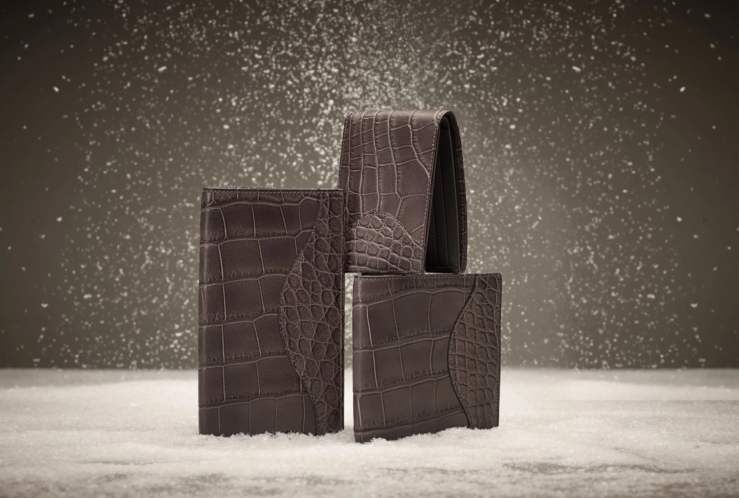 Alligator leather wallet and accessories styled in snowfall setting, Ghurka luxury product art direction by Alexander Mann