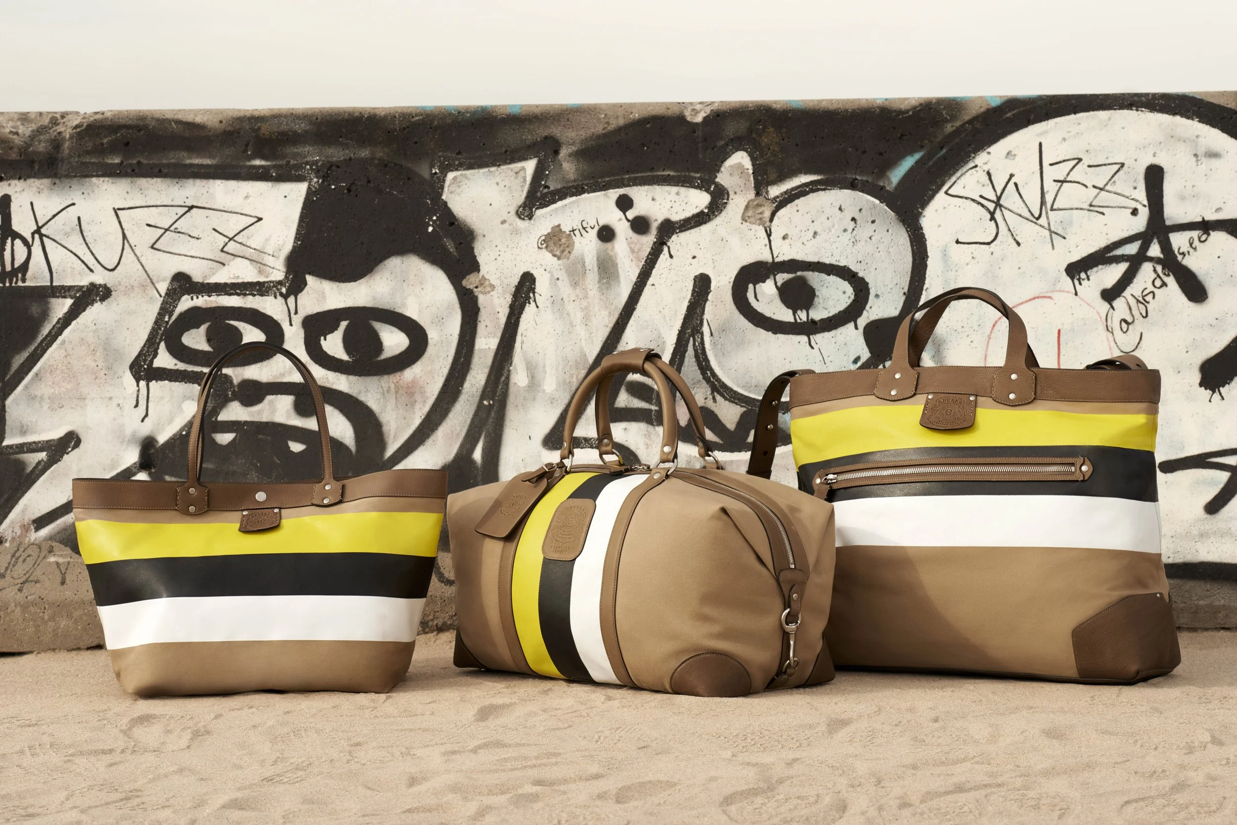 triped leather tote and duffel bags in Ghurka campaign styled against urban graffiti wall, art direction by Alexander Mann