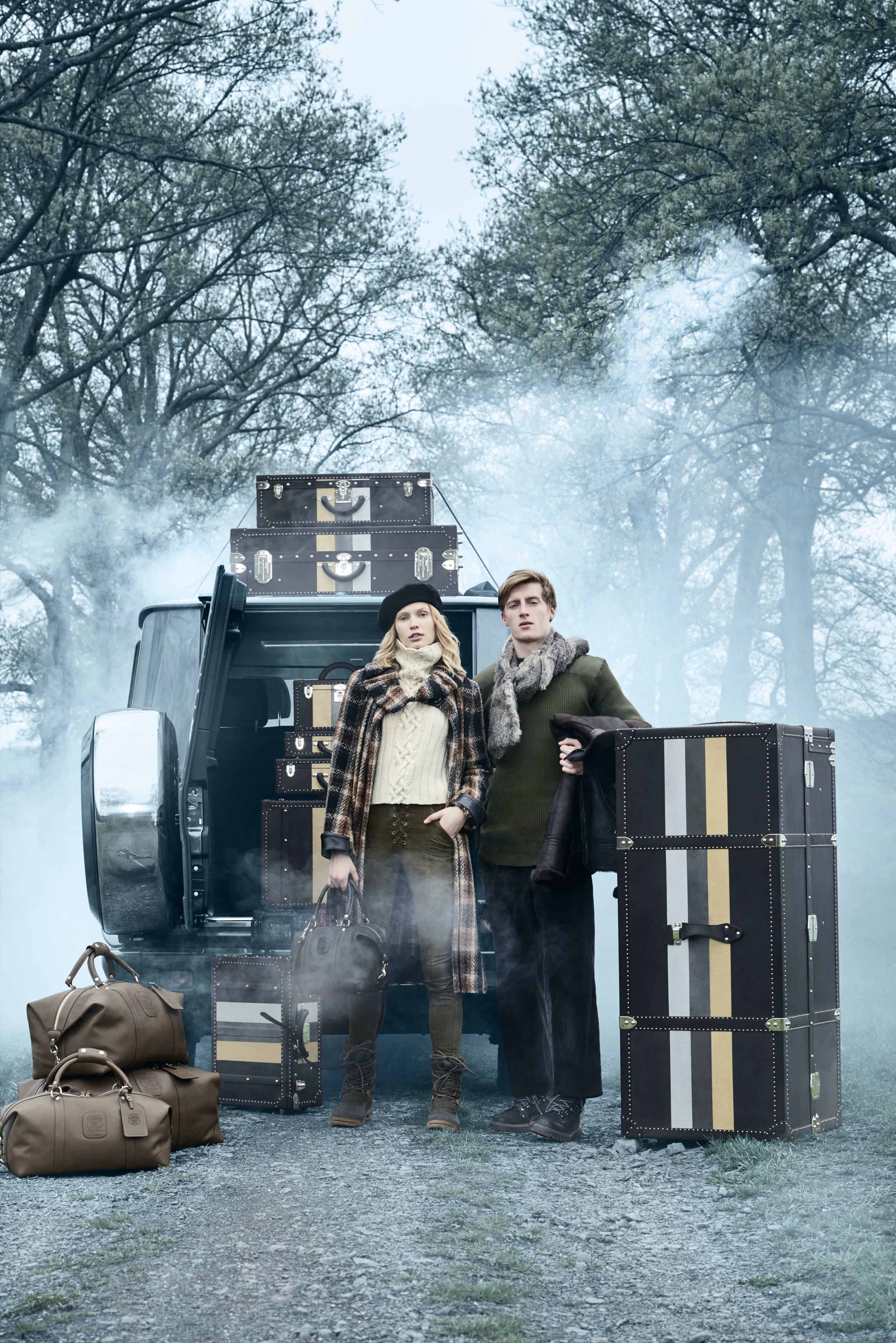 Ghurka campaign with models and leather trunks staged beside a vintage car in a misty landscape, art direction by Alexander Mann