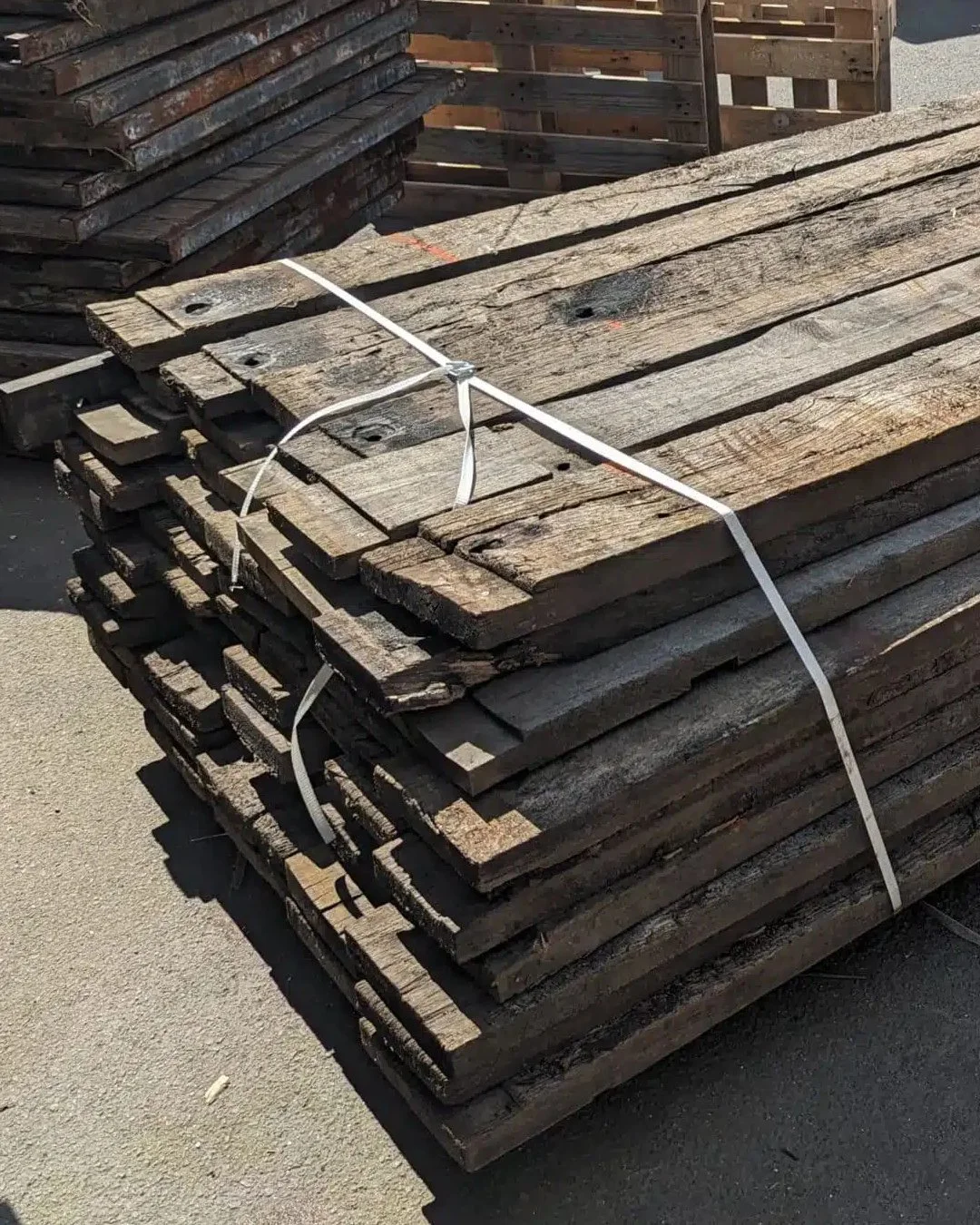 Pile de lames de plancher de fond de wagon empilées avec une sangle blanche prêtes pour le réemploi.