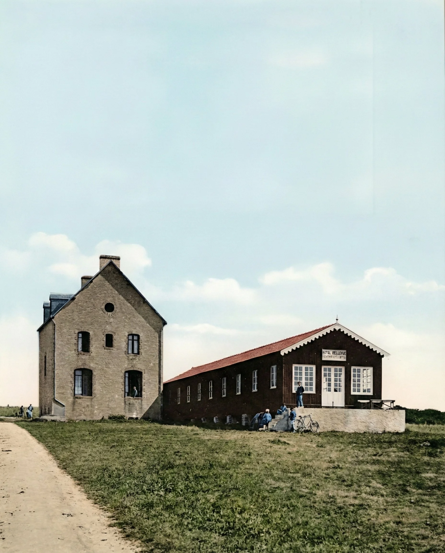 photo ancienne montrant un bâtiment en pierre avec un toit en pente et des fenêtres, et un bâtiment en bois avec un panneau indiquant Hotel Bellevue. Il y a des personnes devant l'hôtel.
