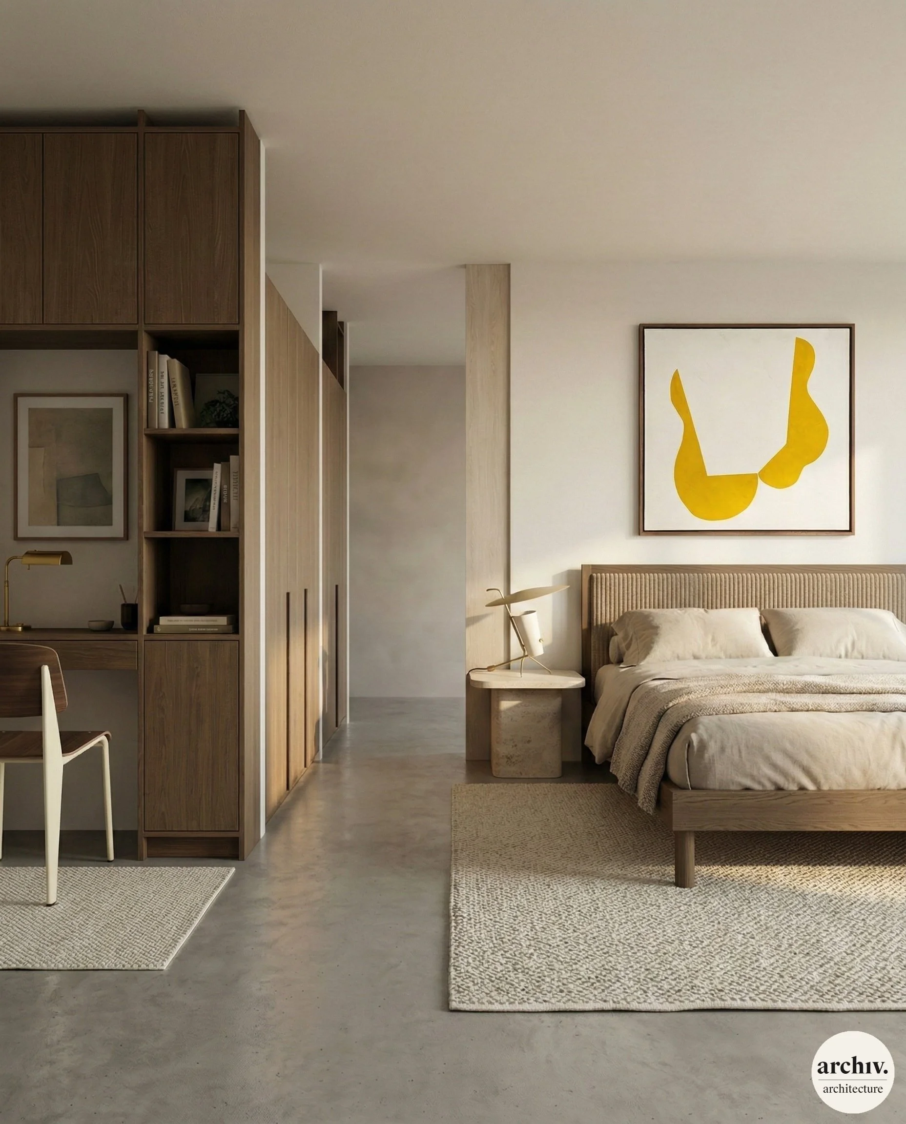 Modern bedroom with beige bedding, a wooden headboard, abstract yellow artwork, bedside table with a sculpture, and a workspace with a wooden desk and bookshelf in the background.  renovated loft Paris.