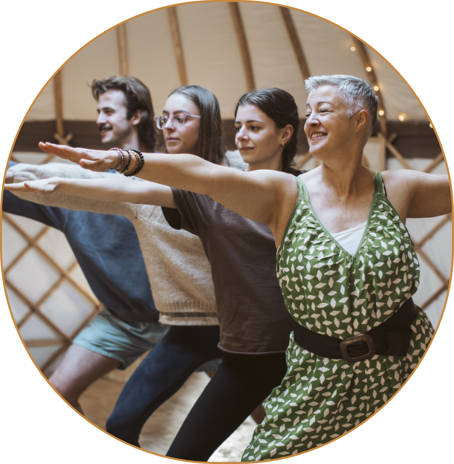Four people in a yoga pose in a studio with warm lighting, practicing yoga together.