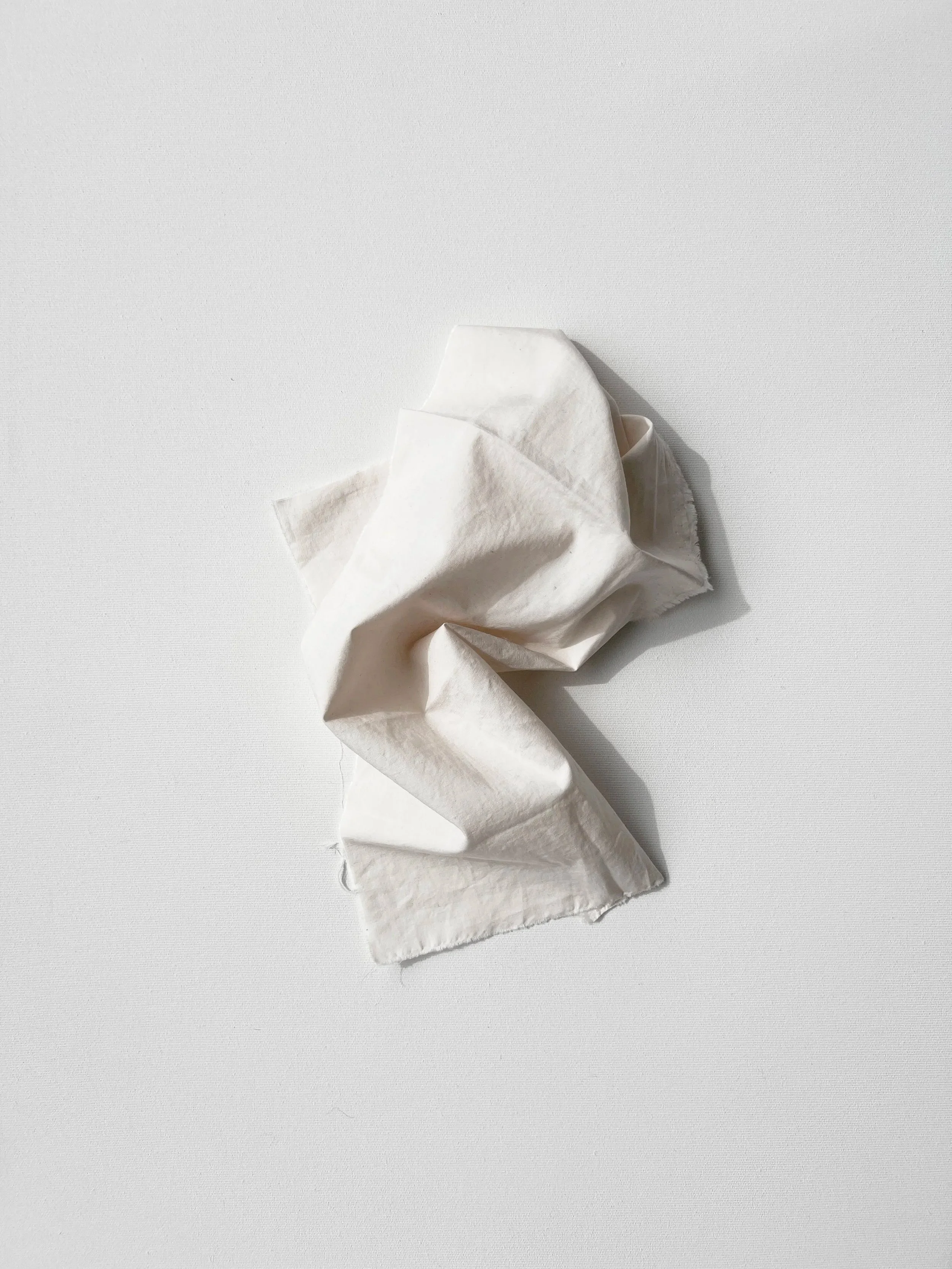 A crumpled white piece of fabric on a white surface.