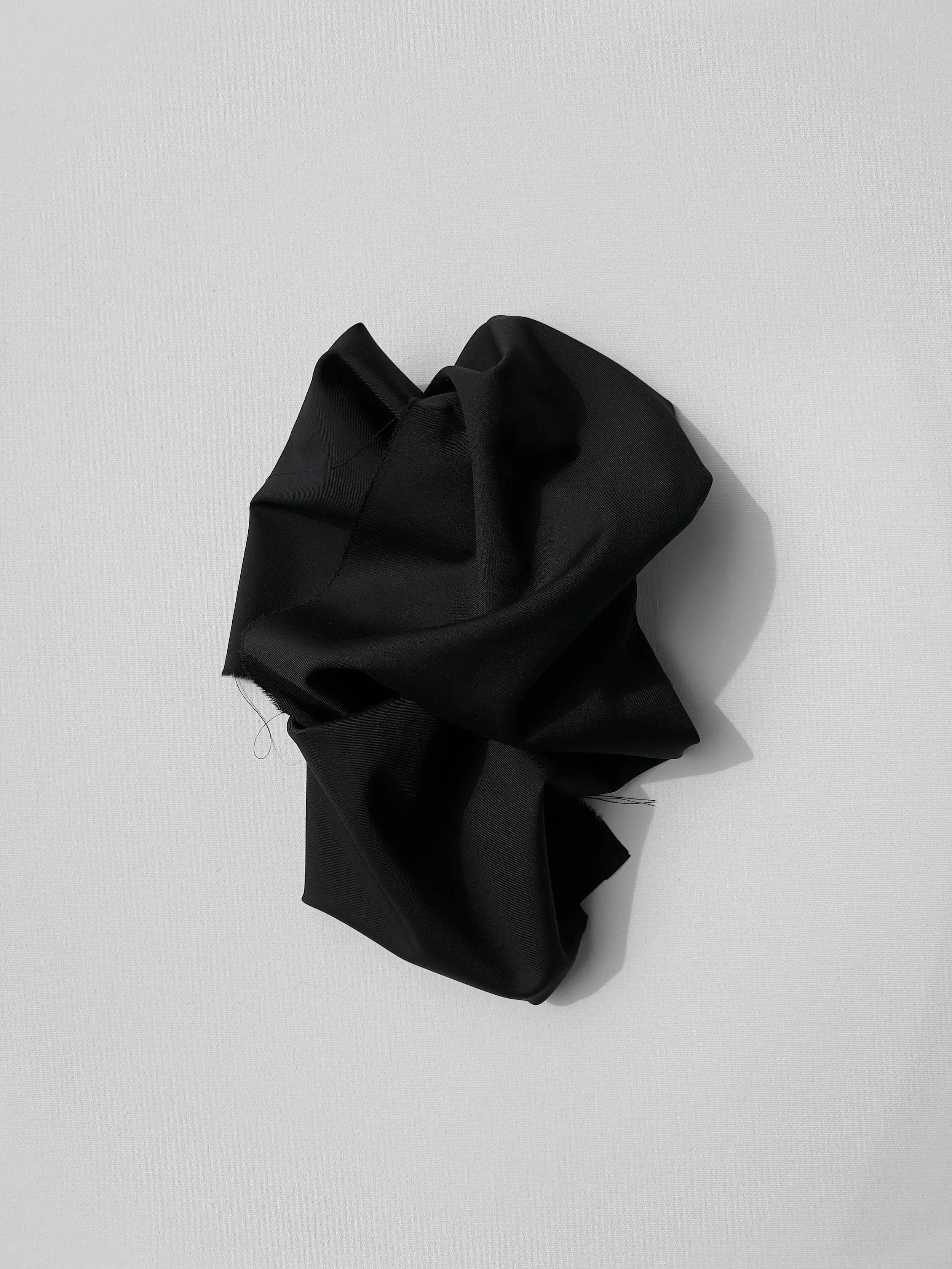 A crumpled black fabric or clothing item on a light grey surface.