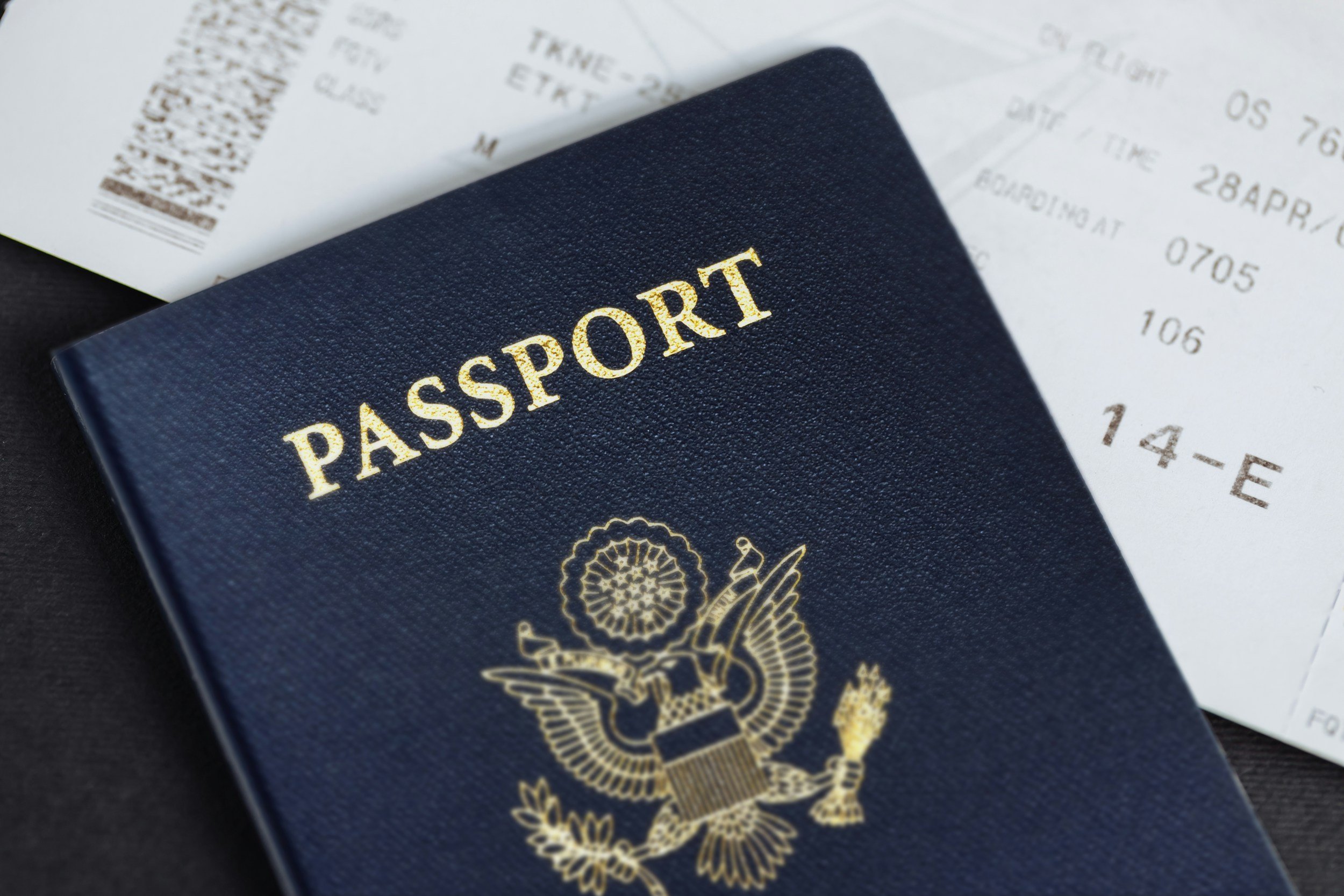 A U.S. passport and a boarding pass on a dark surface.