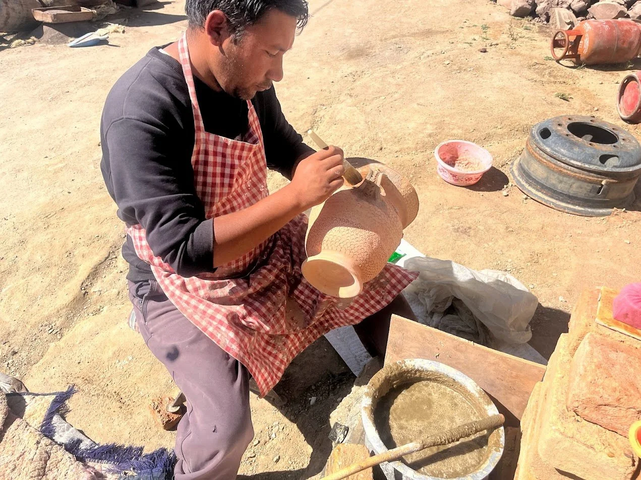 Rigzen boiling the collected Glaze raw material in water and applying it over pots with a brush