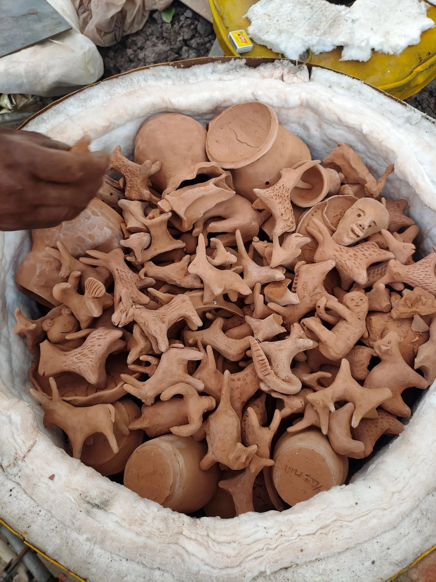A collection of clay pottery and sculptures in a large container.