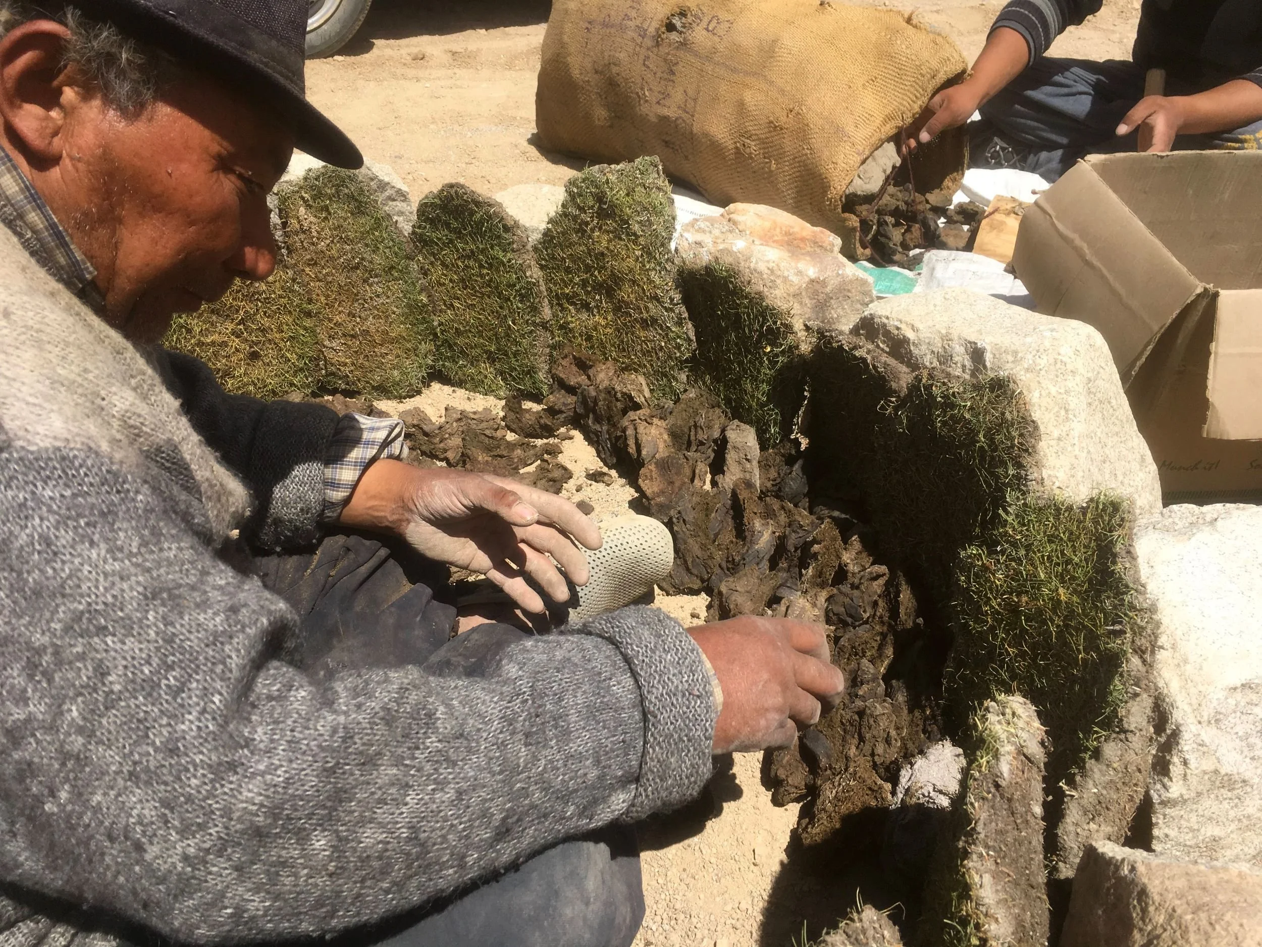 Abbale arranging stones and turf, creating boundary for pit firing