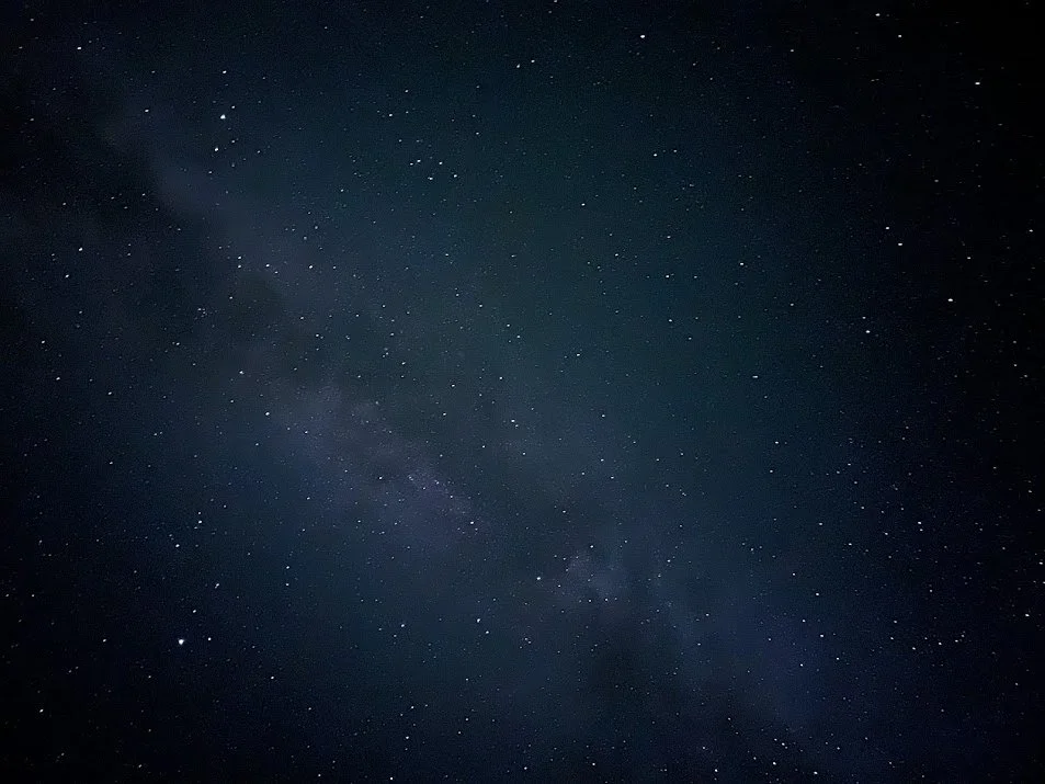 Night sky filled with numerous stars and a faint view of the Milky Way galaxy.