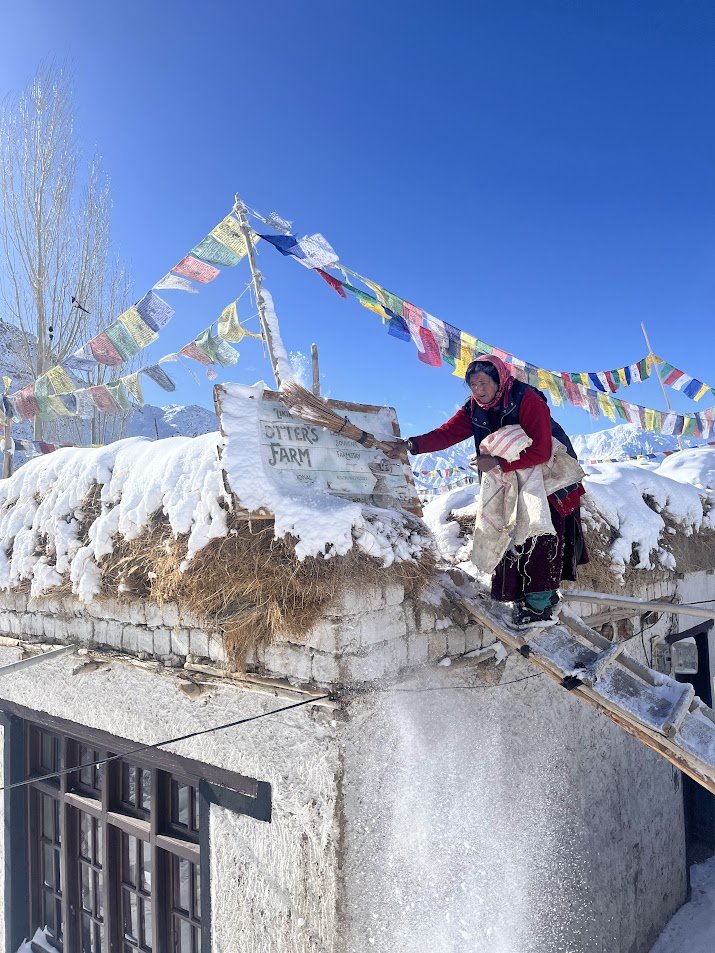 Ammale (Mother) dusing the snow off Likir Pottery signboard
