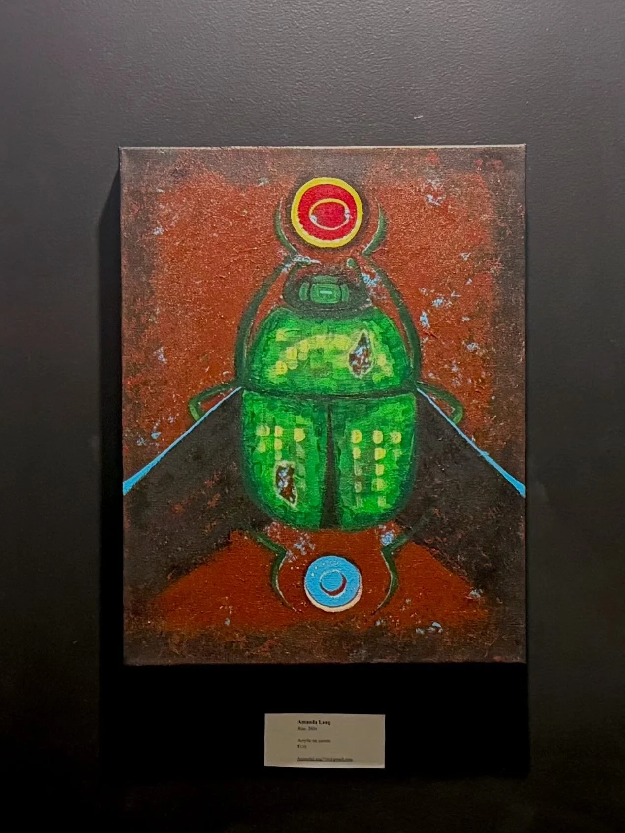 A colorful painting of a stylized green beetle with red and yellow accents, displayed on a black background.