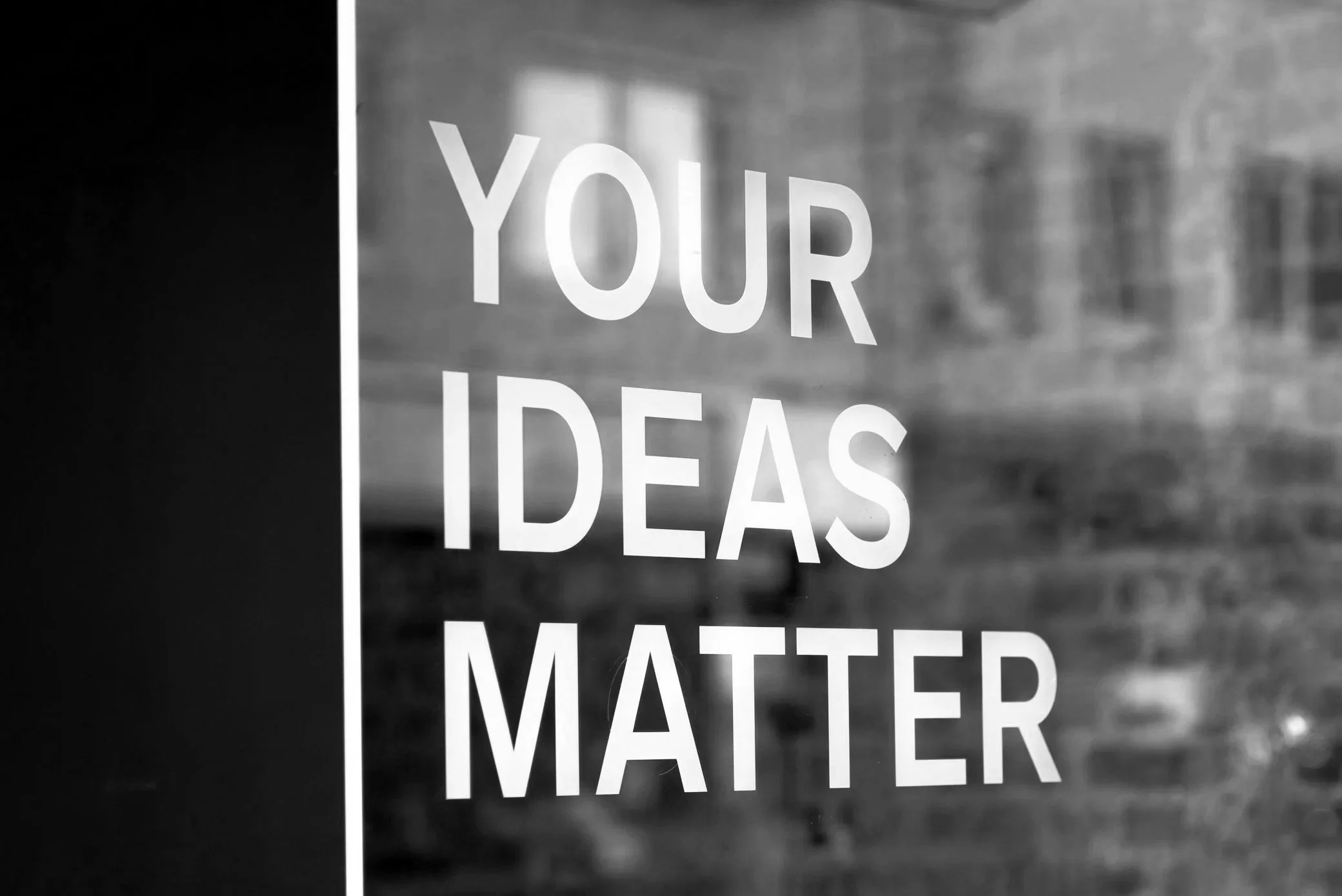 Schriftzug auf einer Glasscheibe mit der Aufschrift "Your Ideas Matter" in Großbuchstaben