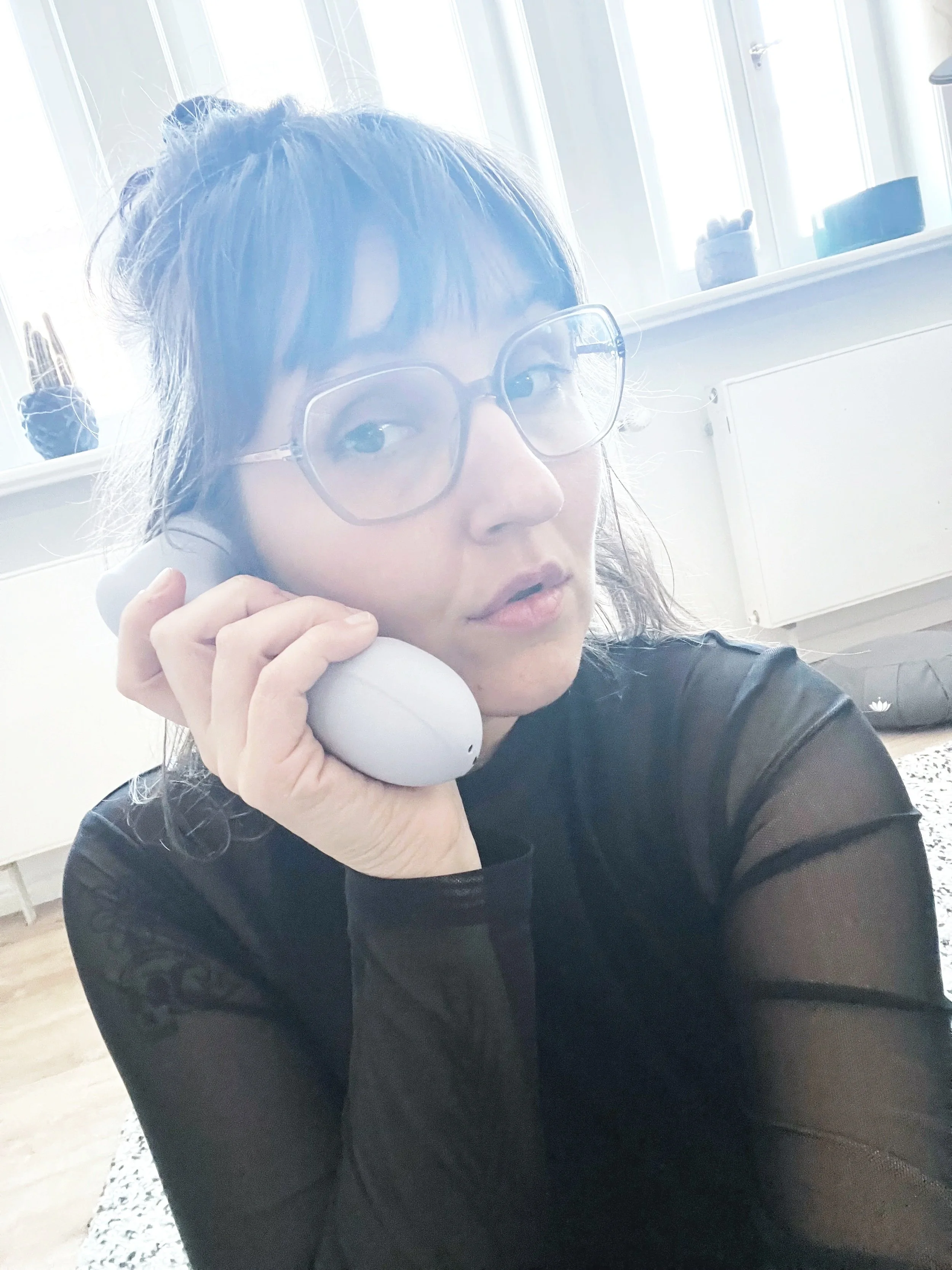 Frau hält ein Lovetoy als Hörer ans Ohr