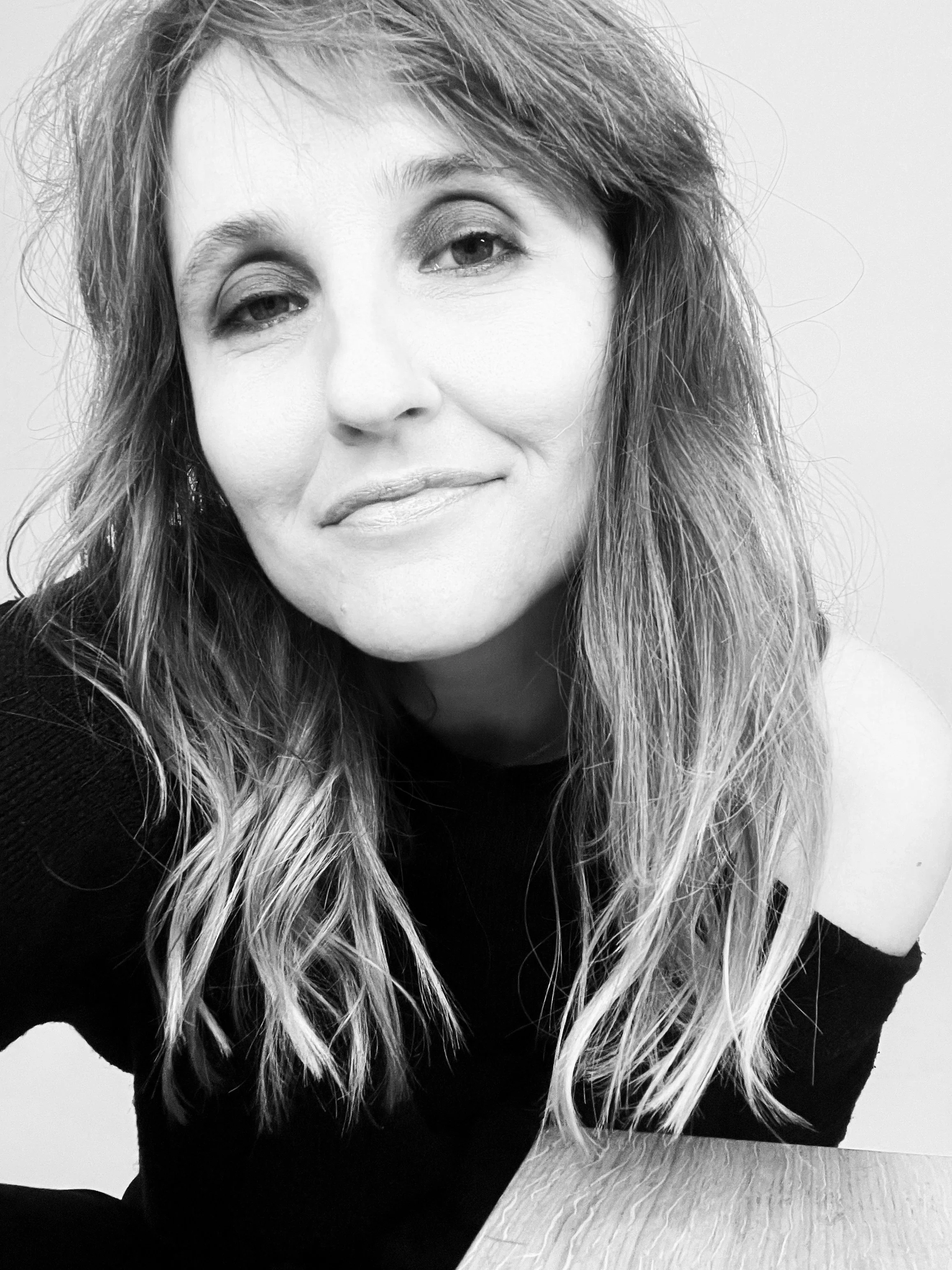 Schwarz-weiß Foto von Olivia Olson mit langen, gewellten Haaren, die leicht lächelt und direkt in die Kamera schaut.