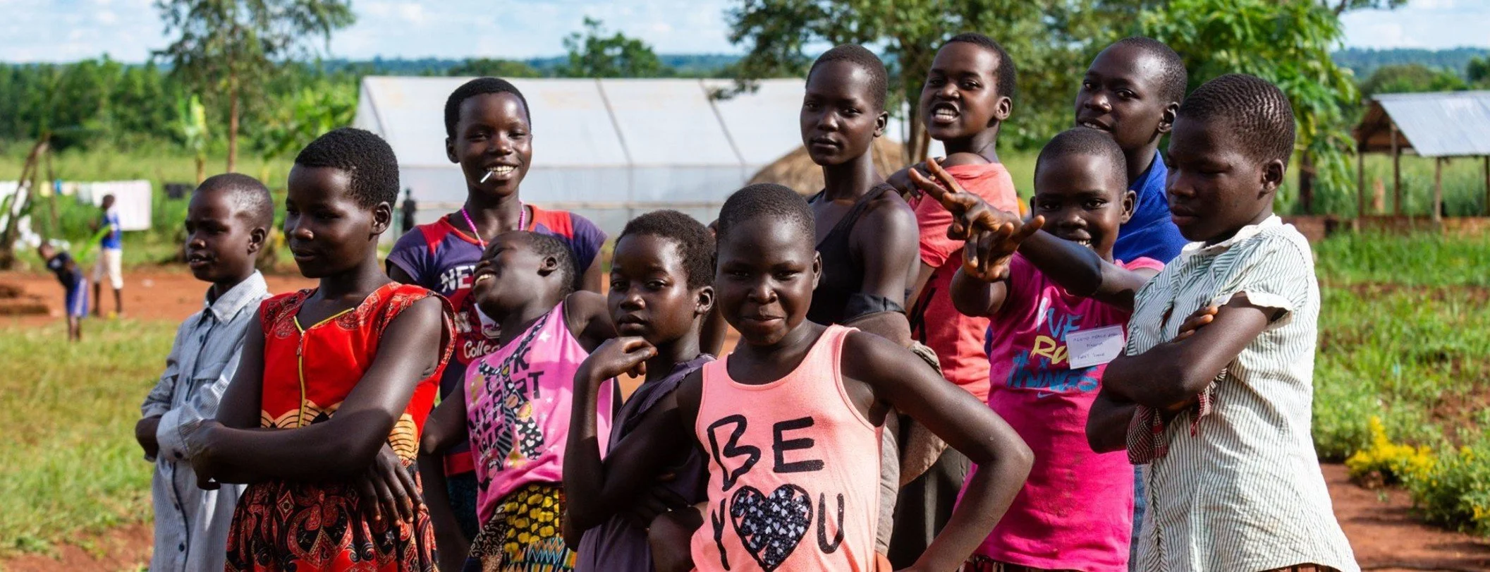 Group of children standing outdoors in a rural area.