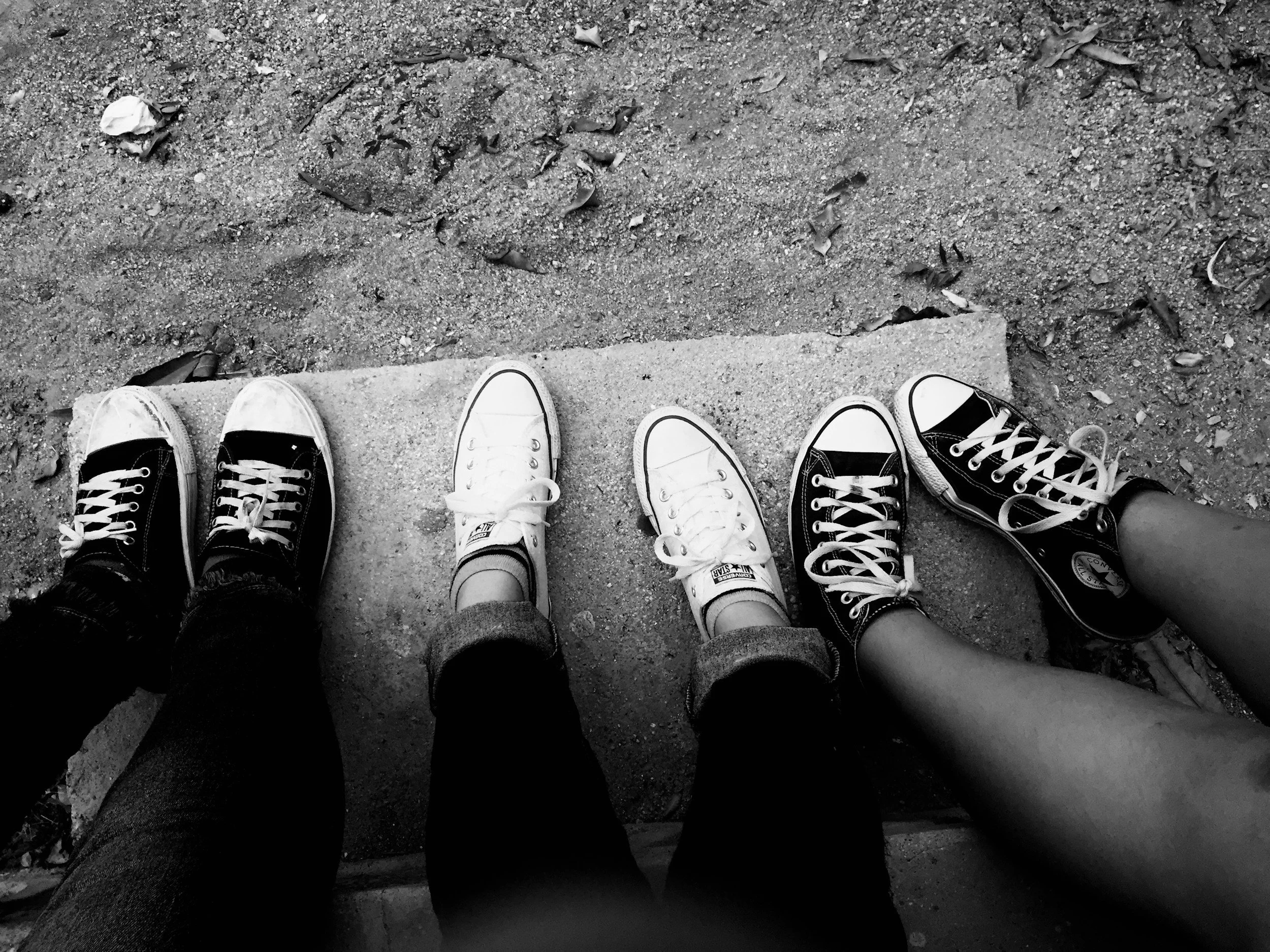Four people sitting with their legs outstretched, wearing roller skates on a concrete surface.