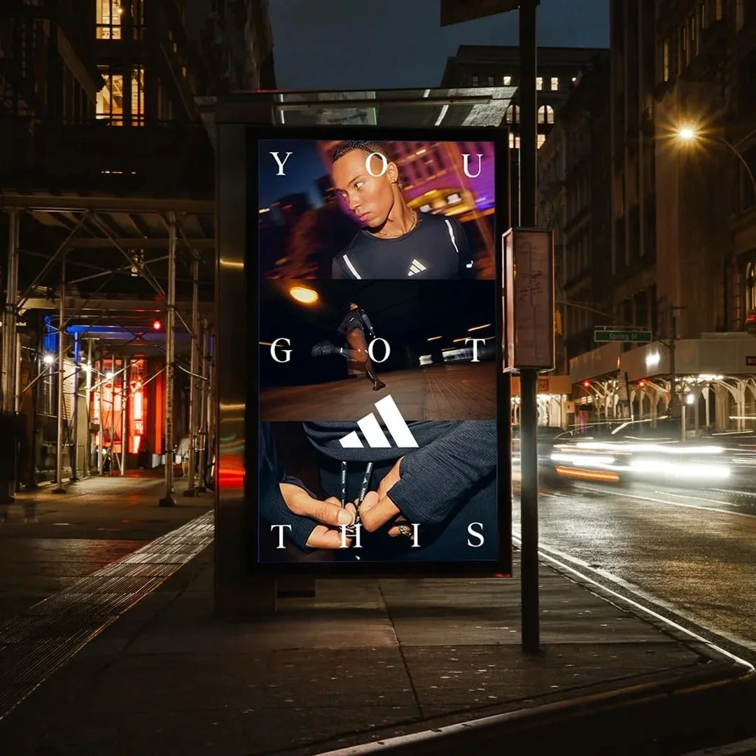 Advertisement billboard at night featuring a young woman with braided hair, a runner in motion in an urban setting, and a close-up of hands wearing dark gloves holding an Adidas logo, with text saying "YOU GOT THIS".