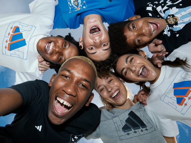 Group of six diverse young people lying in a circle and smiling at the camera.