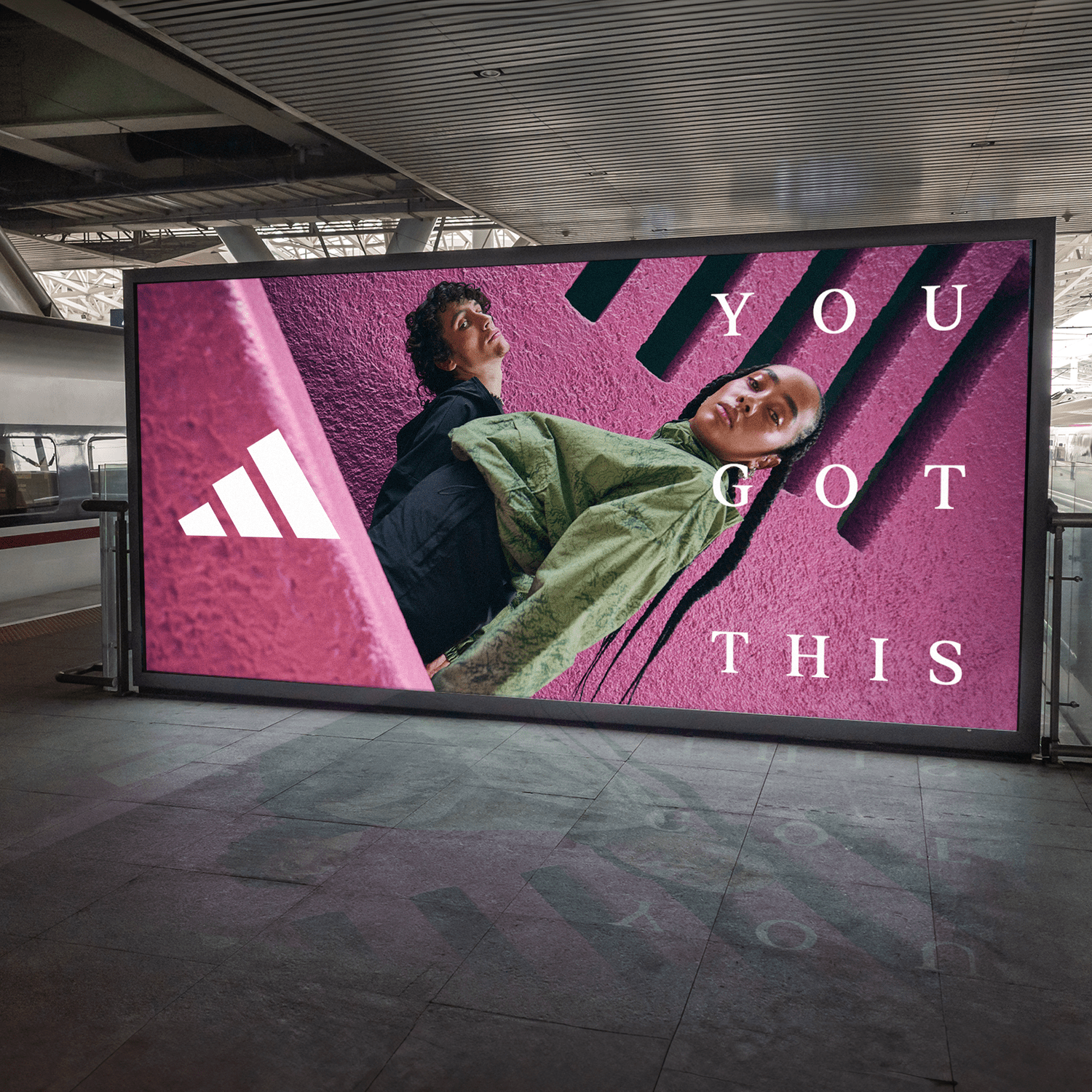 A digital advertisement billboard displaying two models posing against a pink textured wall with black diagonal lines. The text on the billboard reads "You Got This," and there is a white Adidas logo on the left side.