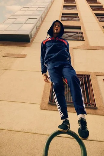 Young man in athletic wear standing on a railing in front of a tall building.