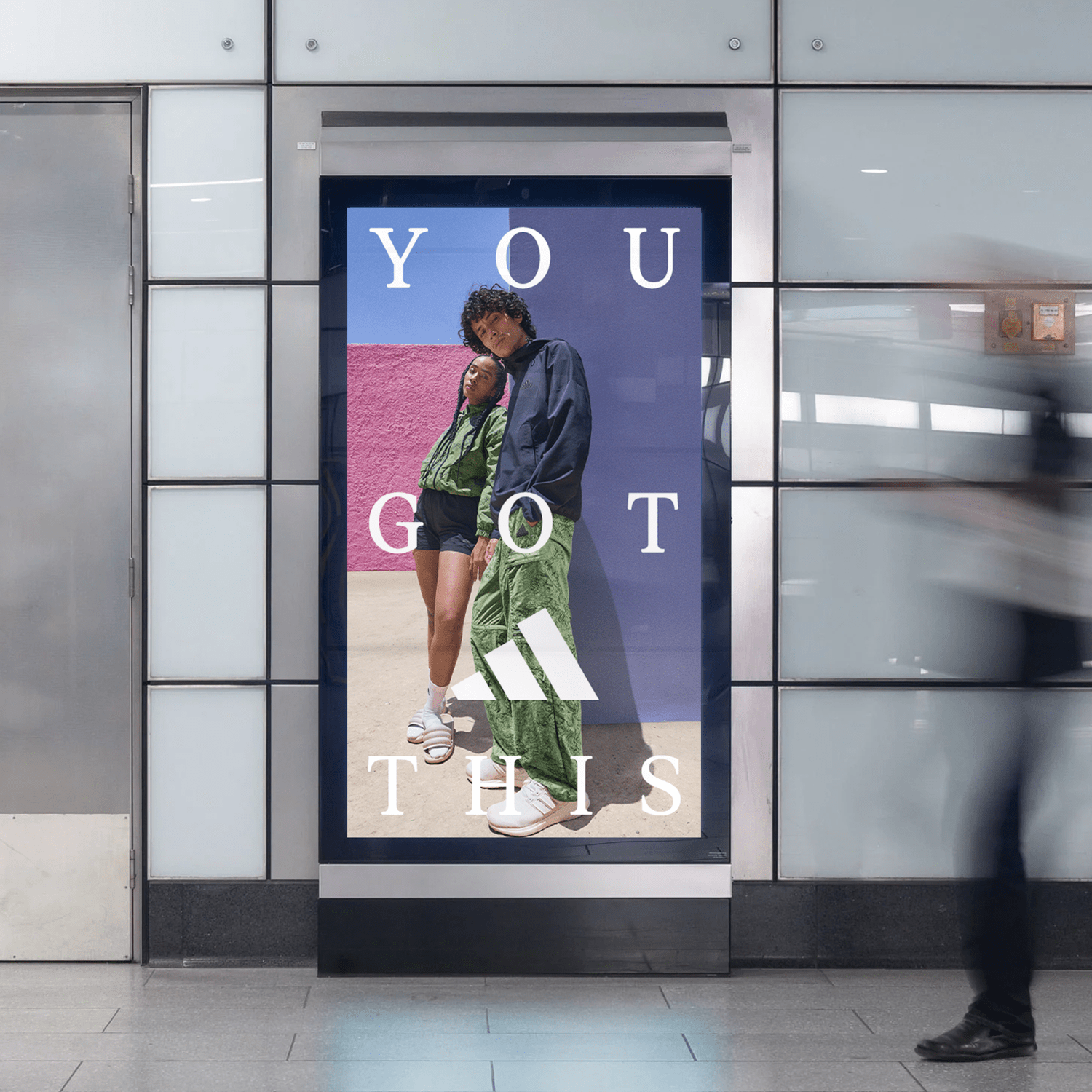 Advertisement poster in a subway station featuring two young models in casual athletic clothing with the text "You Got This" and the Adidas logo.