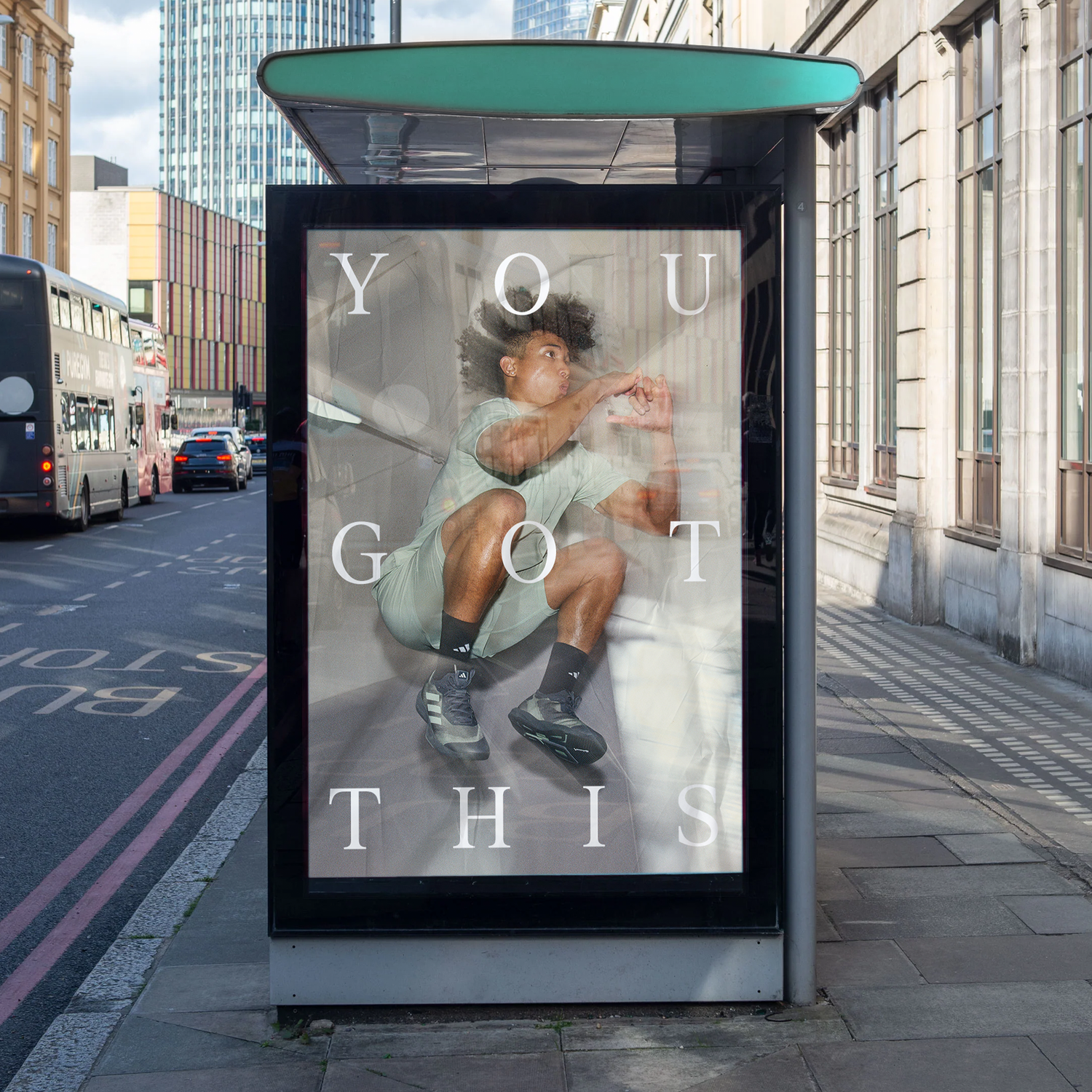 A city bus stop with a large poster of a young man inside a transparent cube, appearing to crouch and punch the glass. The poster has the text 'YOU GOT THIS' overlaid in large white lettering.