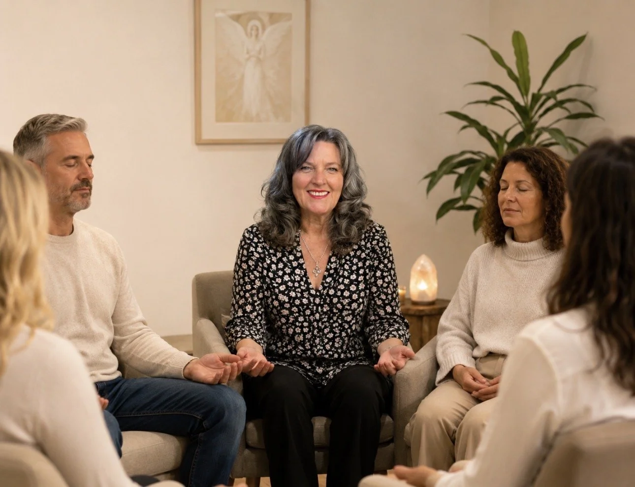 Group of people sitting in circle with eyes closed during meditation in a cozy room