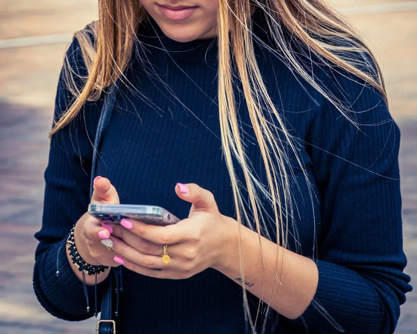A woman typing a text message on her smartphone, highlighting high-open-rate SMS marketing campaign management for local businesses.