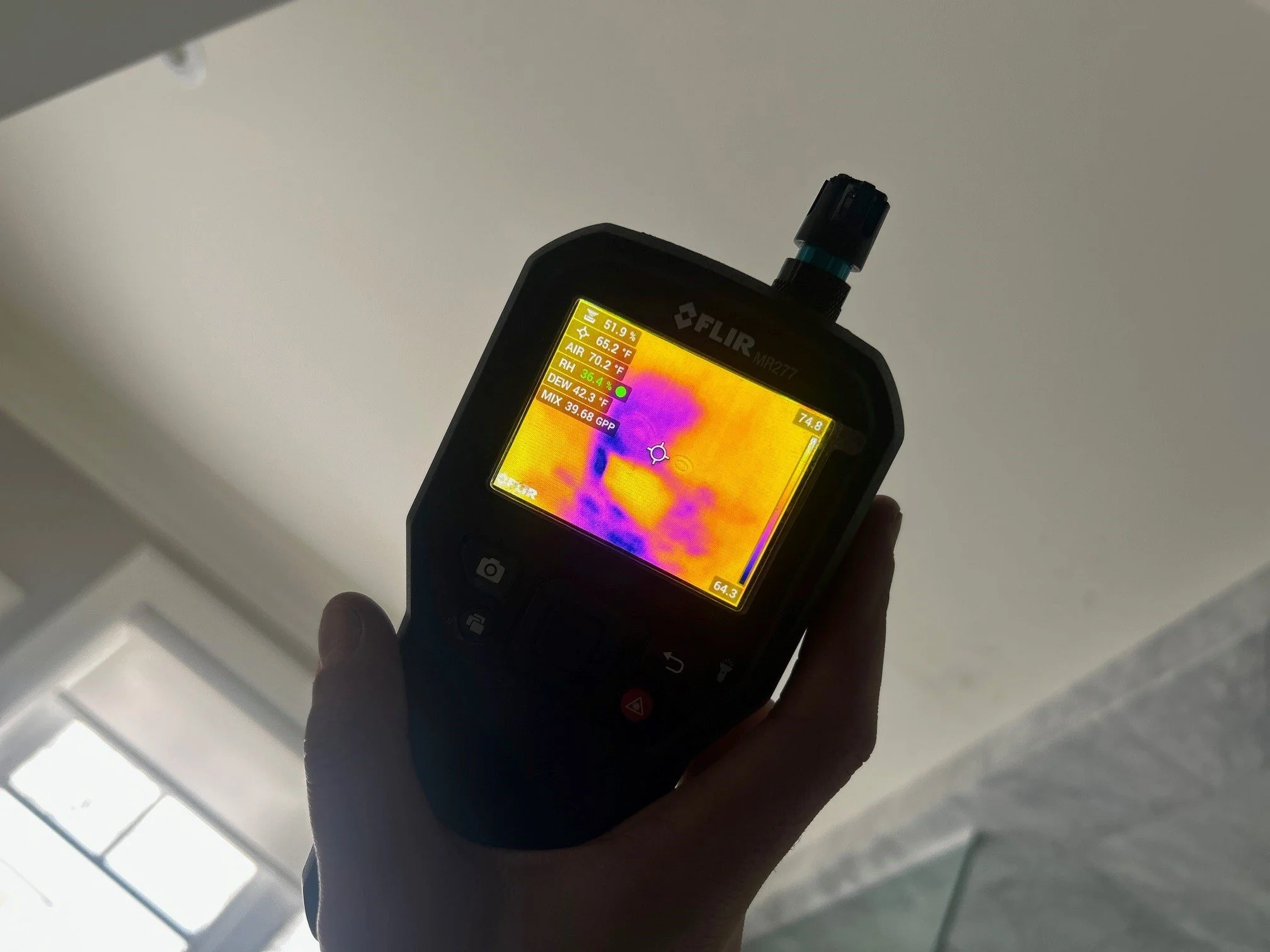 Infrared thermal imaging device showing a heat map with colors indicating temperature variations.