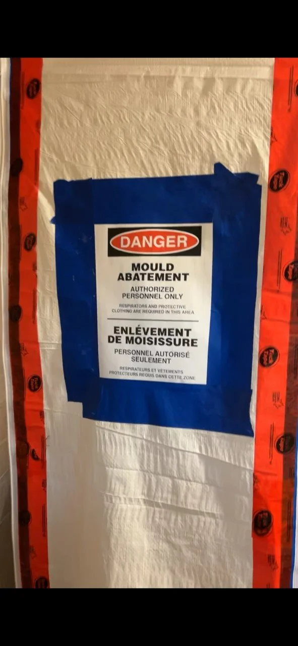 Warning sign on a door indicating a mold abatement area, authorized personnel only, with instructions in English and French.