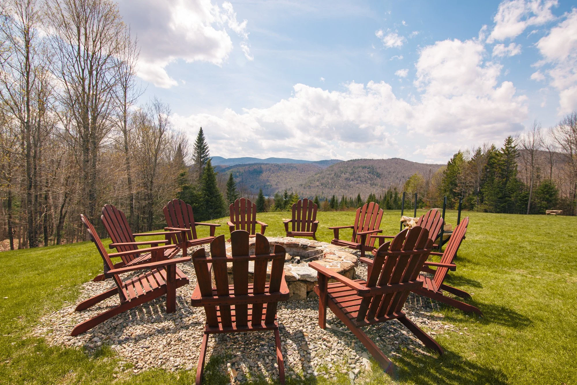 An image of a circle of Adirondack chairs around a fire pit overlooking the view at Garnet Lodge