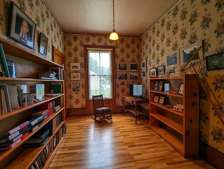 A charming view of a reading room with hardwood floors and a rocking chair in the Johnsburg Historical Society.