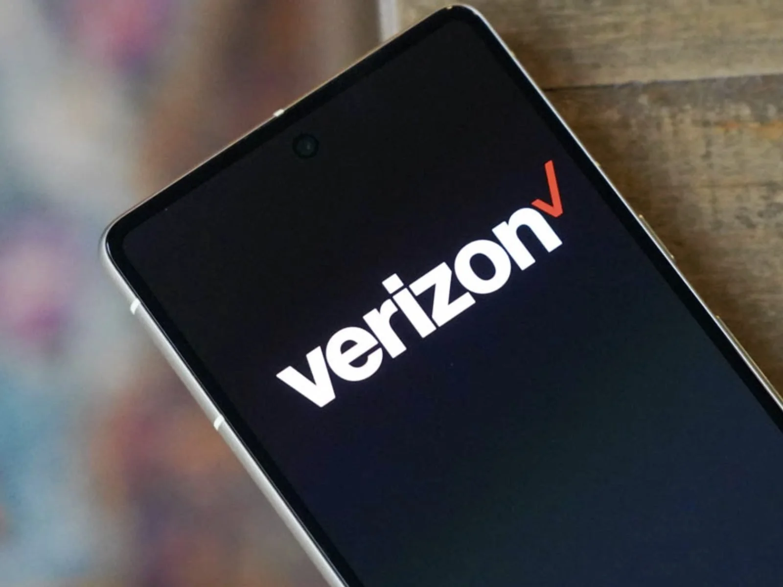 Close-up of a smartphone screen displaying the Verizon logo on a black background.