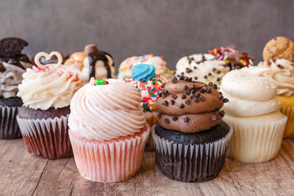 Assorted cupcakes with frosting and toppings on a wooden surface