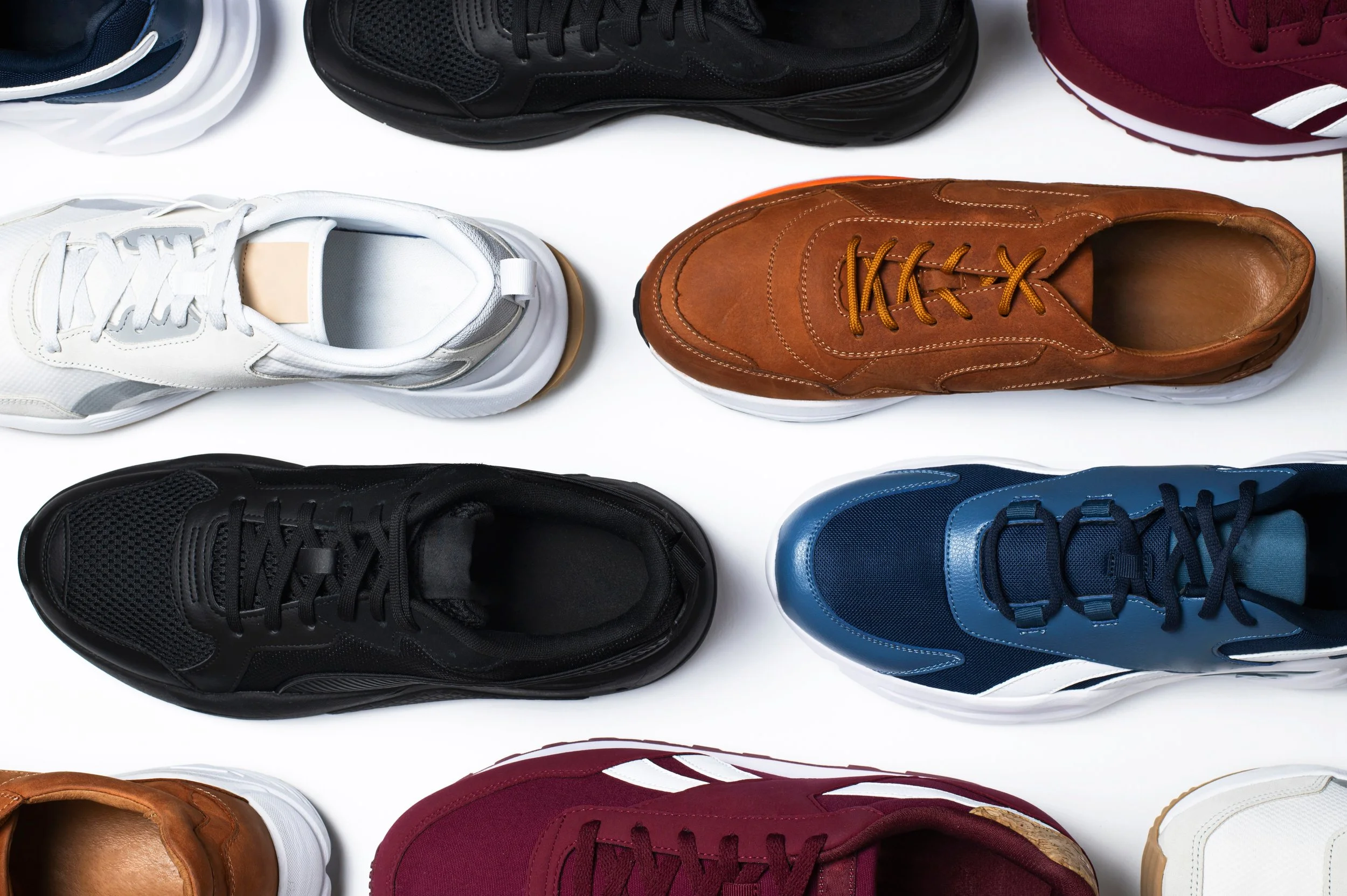 A variety of athletic shoes in different colors and styles arranged on a white background.