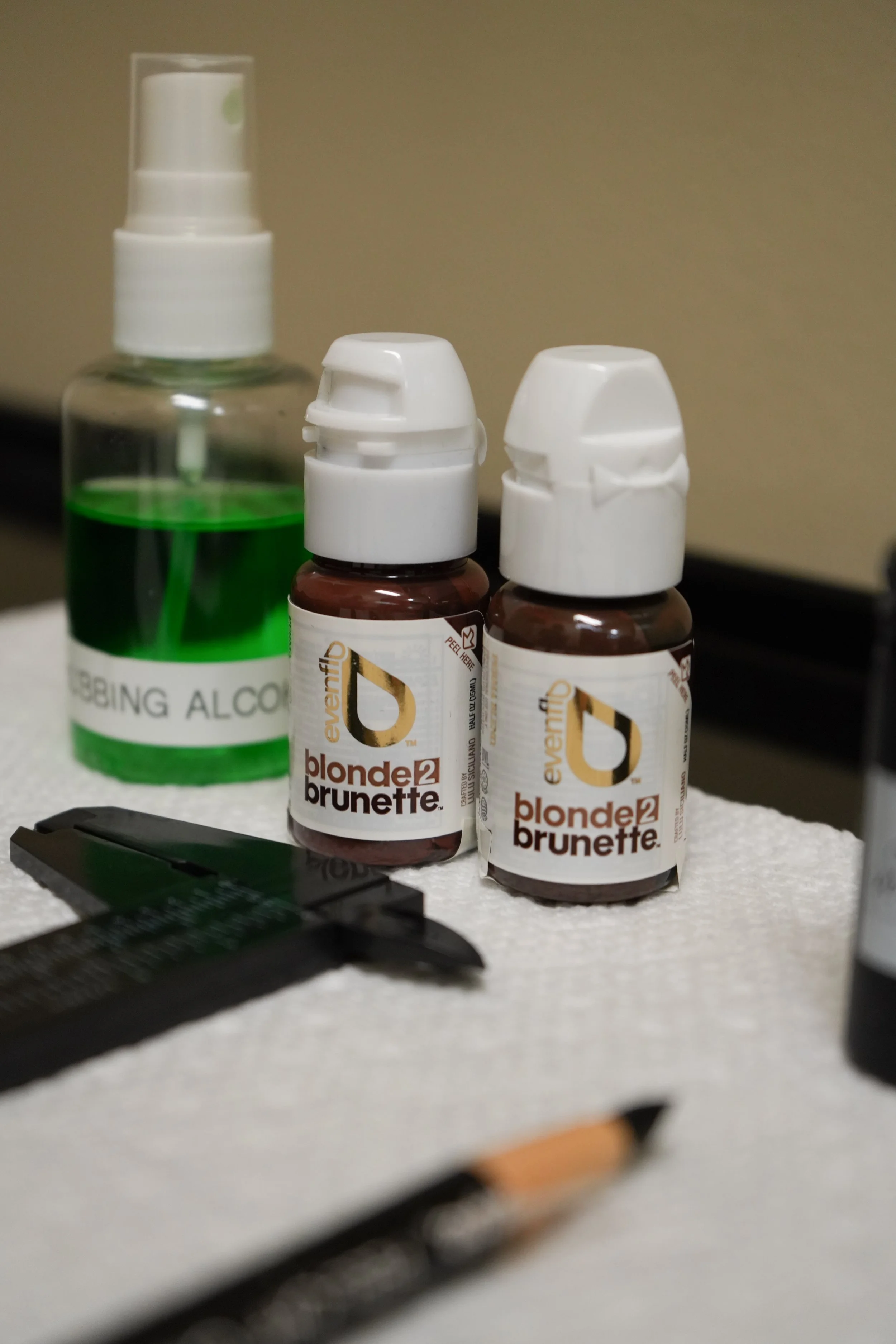 A bottle of rubbing alcohol with a spray nozzle and two bottles brow pigment for a permanent make up service.
